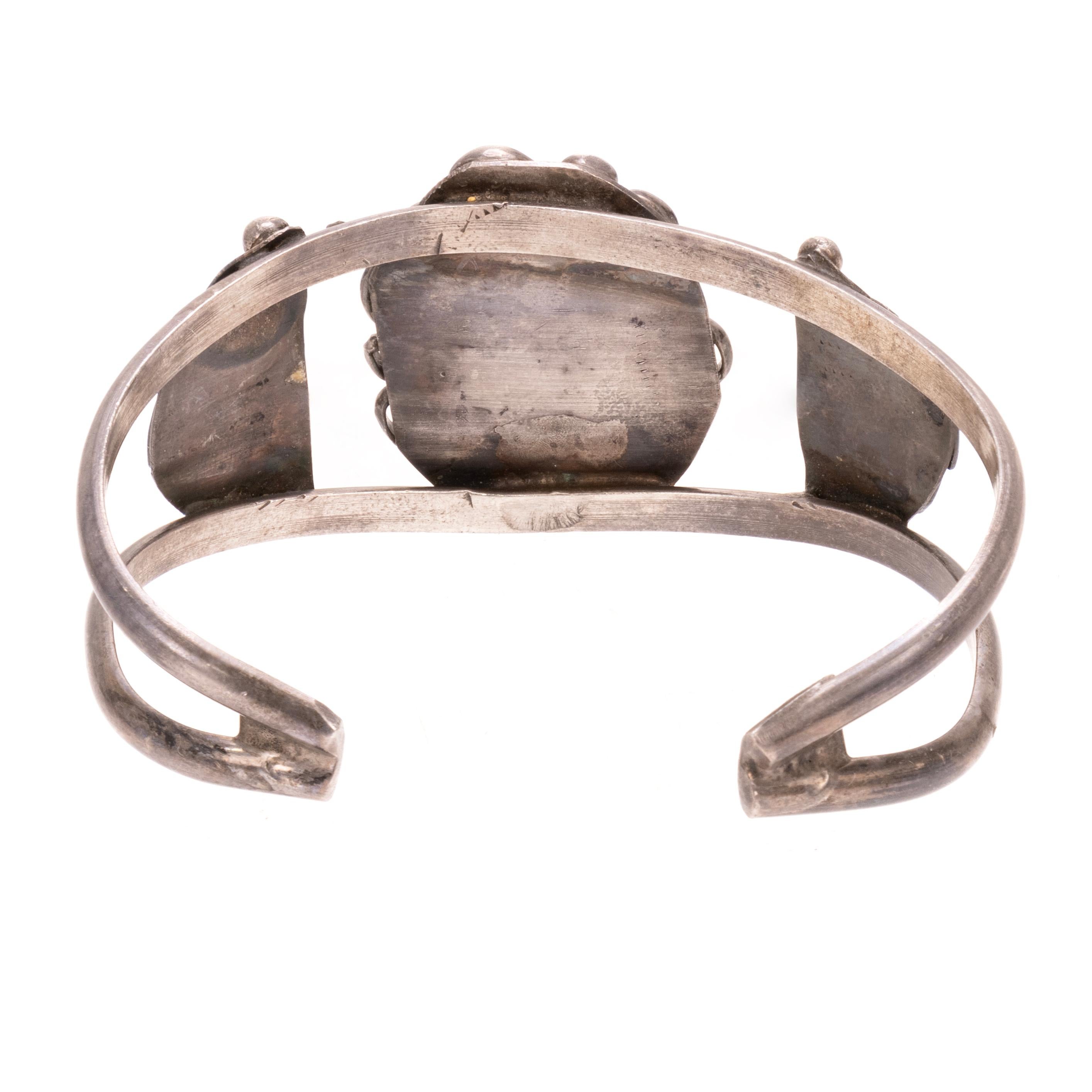 Bracciale in turchese e argento sterling della Bella Addormentata. Design aperto su sterlina con pietra centrale singola. La pietra è circondata da un bordo in corda attorcigliata e da un design smerlato con piume in sterling su entrambi i lati. La