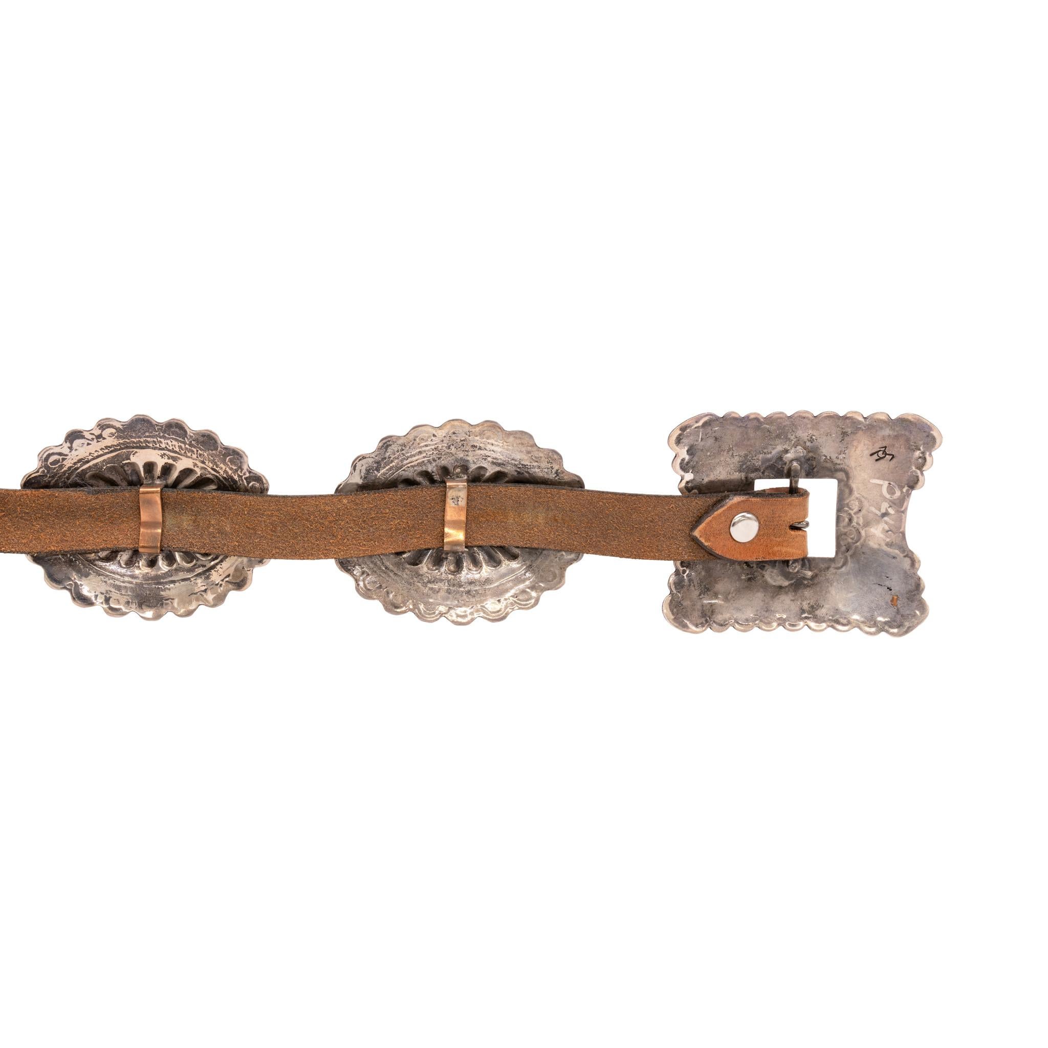 Navajo sterling silver and turquoise concho belt. Seven oval conchos with single stone of Cerrillos turquoise in center. Conchos are stamped with traditional designs having scalloped edges. Buckle is rectangle in shape with four Cerrillos stones and