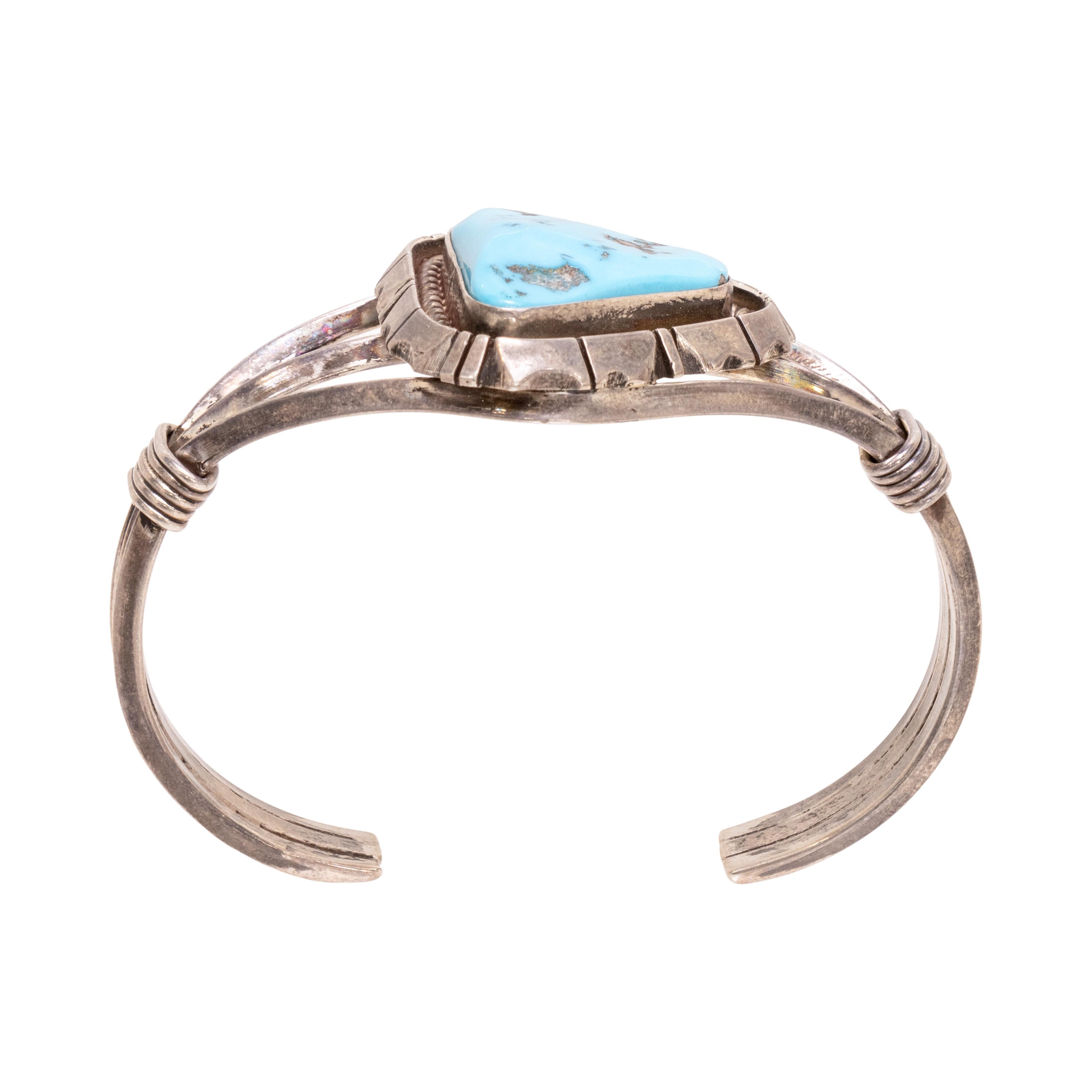 Bracciale in turchese Navajo e argento sterling. Con una singola pietra con taglio a triangolo incastonata in un castone con corda attorcigliata e bordo decorativo a tratteggio. Incastonato in un insolito bracciale a tre fasce con un dettaglio di