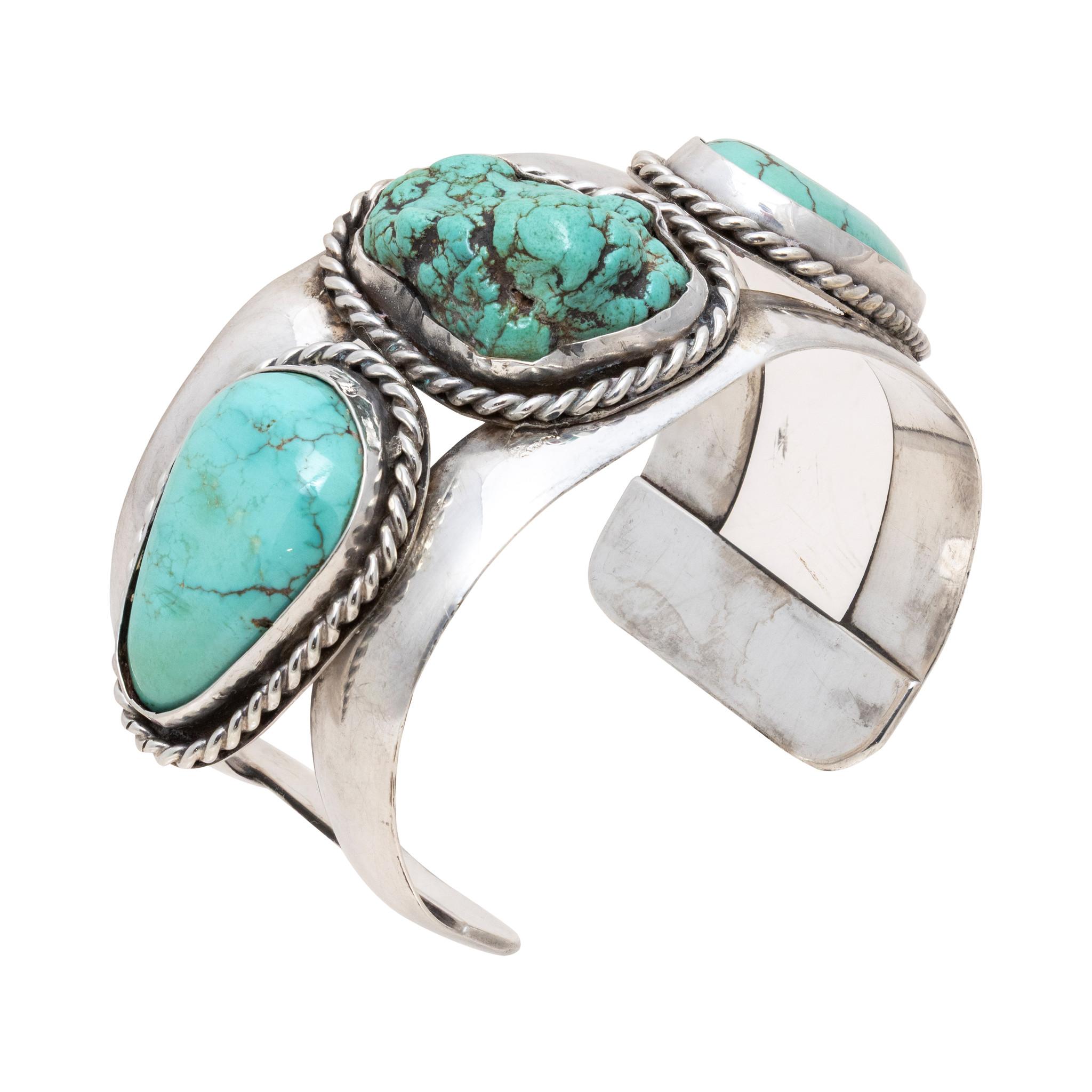 Bracciale Navajo Kingman in turchese e argento sterling. Tre grandi pietre naturali e non trattate, ognuna in un castone liscio con bordo in corda ritorta. La pietra centrale non è lucidata, le pietre laterali sono lucidate e tagliate a forma di