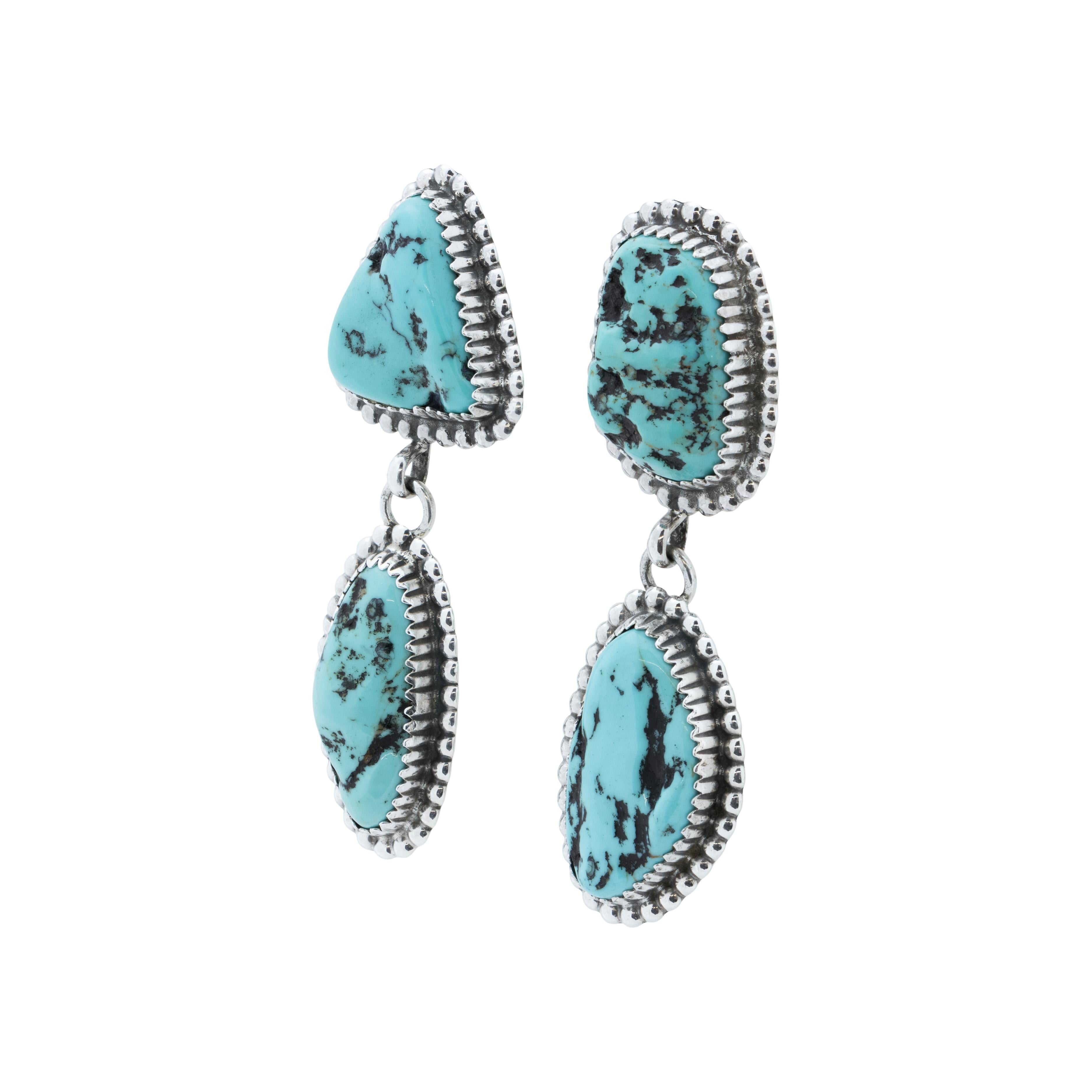 Orecchini pendenti a due pietre in turchese navajo e argento sterling dell'argentiere Navajo Avin Joe. Ogni orecchino ha due pietre, la parte superiore è fissata a un perno e la parte inferiore è collegata a un anello per il movimento. Pietre