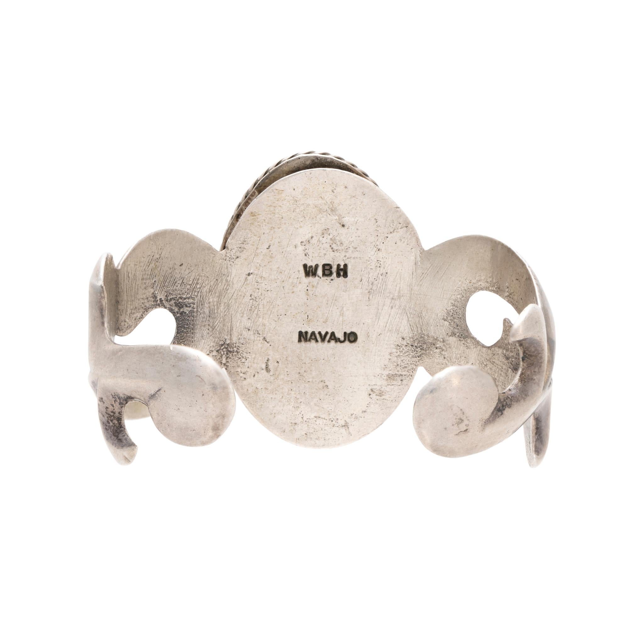 Brazalete Navajo de plata de ley moldeada en arena con piedra central de turquesa Kingman. La piedra es de un hermoso azul claro con matriz marrón, engastada con un diseño de cuerda retorcida. Sujeta a una robusta banda de fundición de arena con