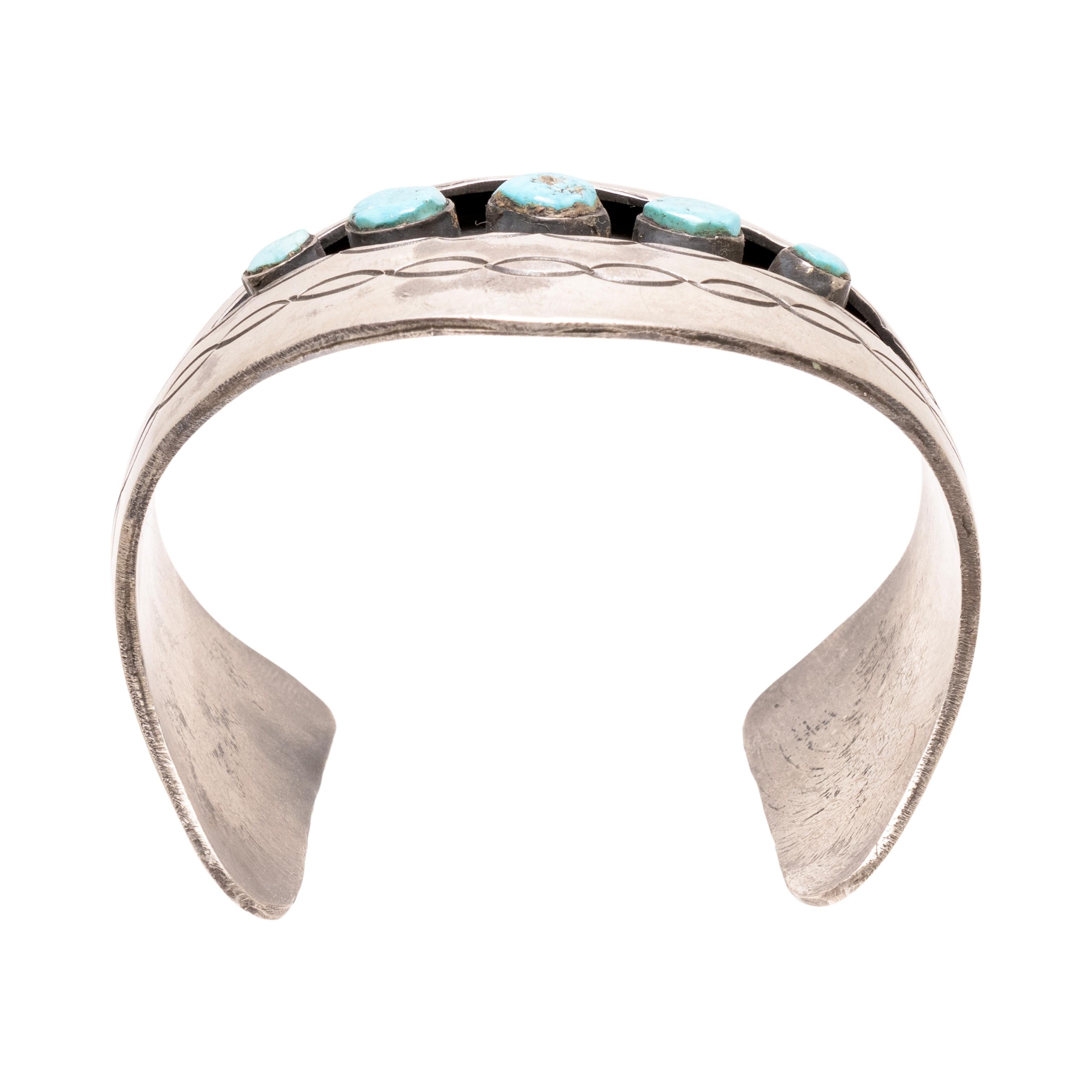 Bracciale shadowbox in turchese Navajo e argento sterling. Con cinque pietre di turchese Kingman in shadowbox, incastonate in un bracciale di sterlina massiccia con dettagli stampati. Le pietre sono di un blu brillante con una minima matrice marrone
