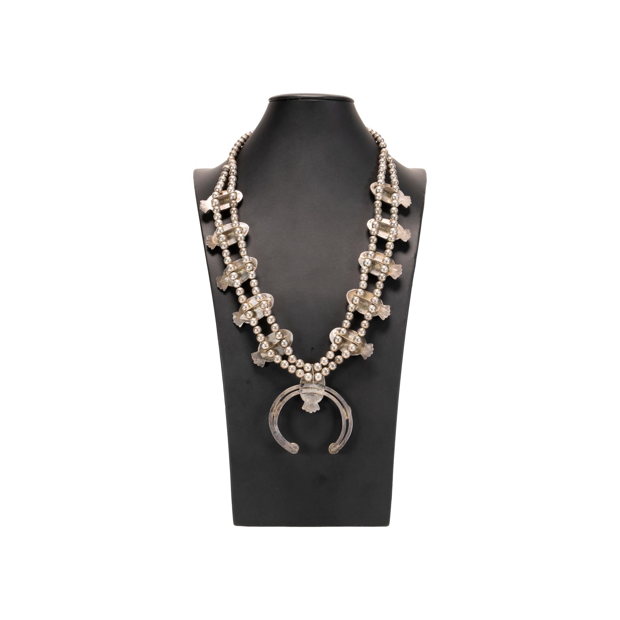 Navajo Morenci turquoise and sterling squash blossom necklace. Ten natural stones in shadow box design ending in a matching additional 5 stone naja. Stones are a bright light blue with brown veined matrix. Great patina on silver. No maker's mark.