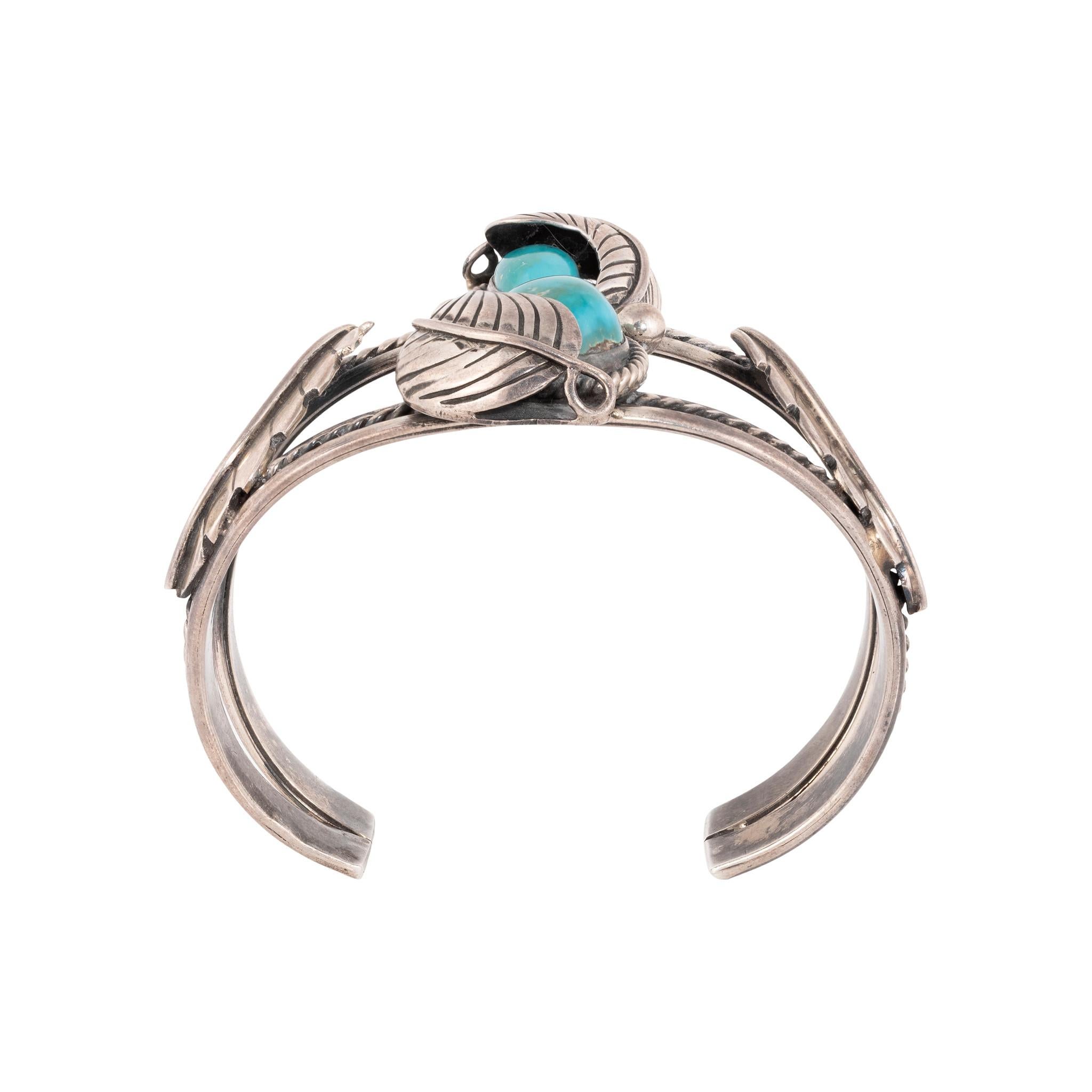 Bracciale Navajo Carico Lake in turchese e argento sterling. Due pietre in rilievo semi-nascoste sotto un dettaglio di piume d'argento con accenti di perline in argento. Le pietre sono di un blu intenso con una grande profondità e una matrice