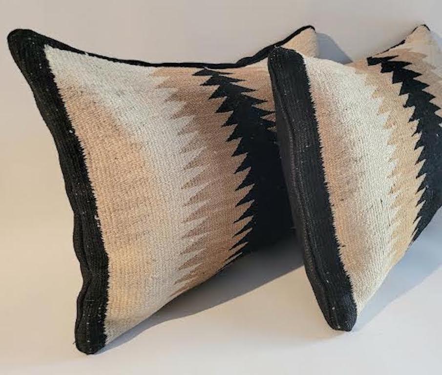 Pair of Navajo Weaving Pillows. Custom made with antique Navajo weaving and a black linen backing. Pillows are made with zippers for cleaning and have feather down inserts. Colors are Beige, Black, and off white.

Pair of pillows 13 x 20.