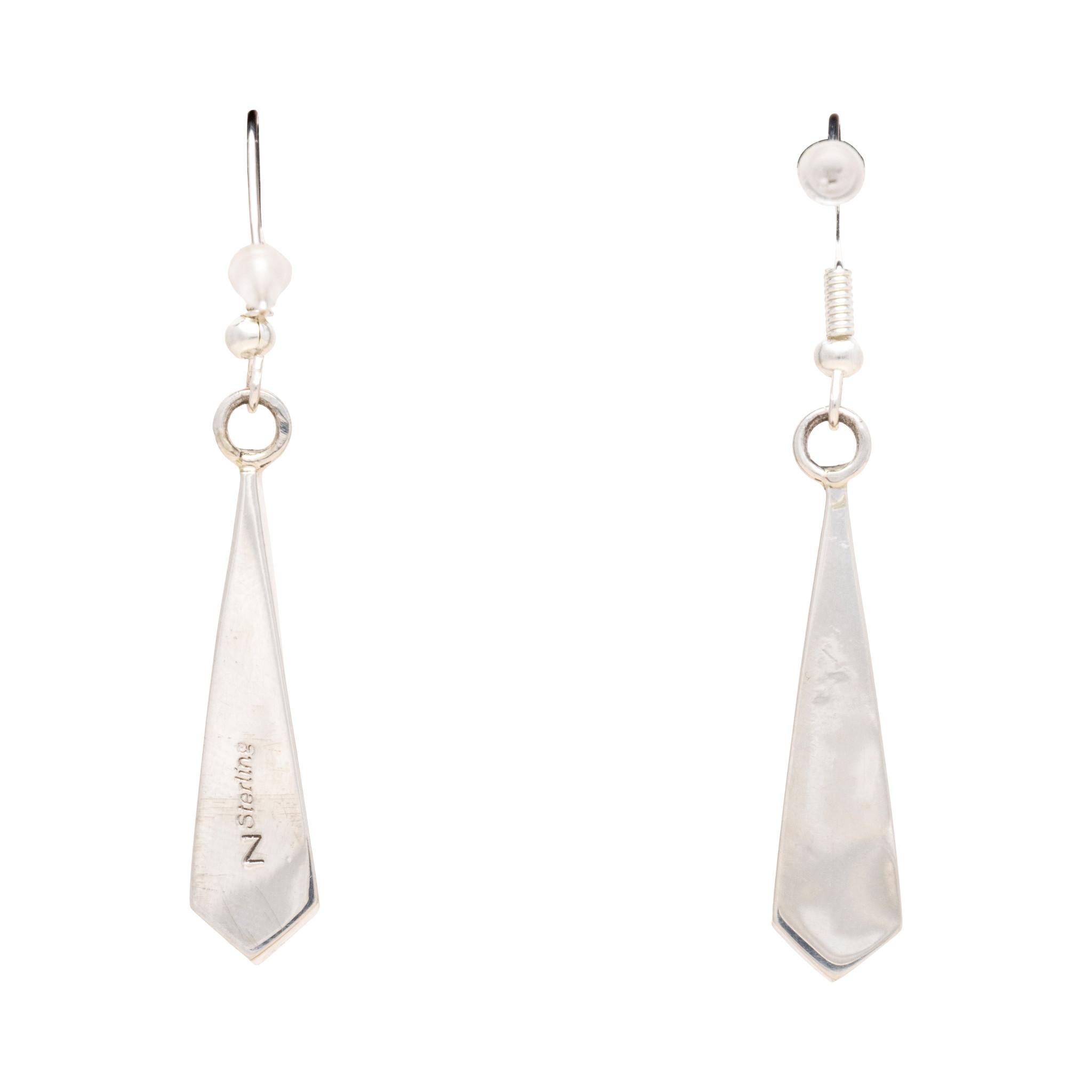 Orecchini pendenti in turchese Navajo White Buffalo e argento sterling. Realizzato dall'argentiera Navajo Mary Yazze. Le pietre sono di colore bianco e nero e hanno una forma a goccia appuntita, intarsiate nel retro in sterling non decorato con