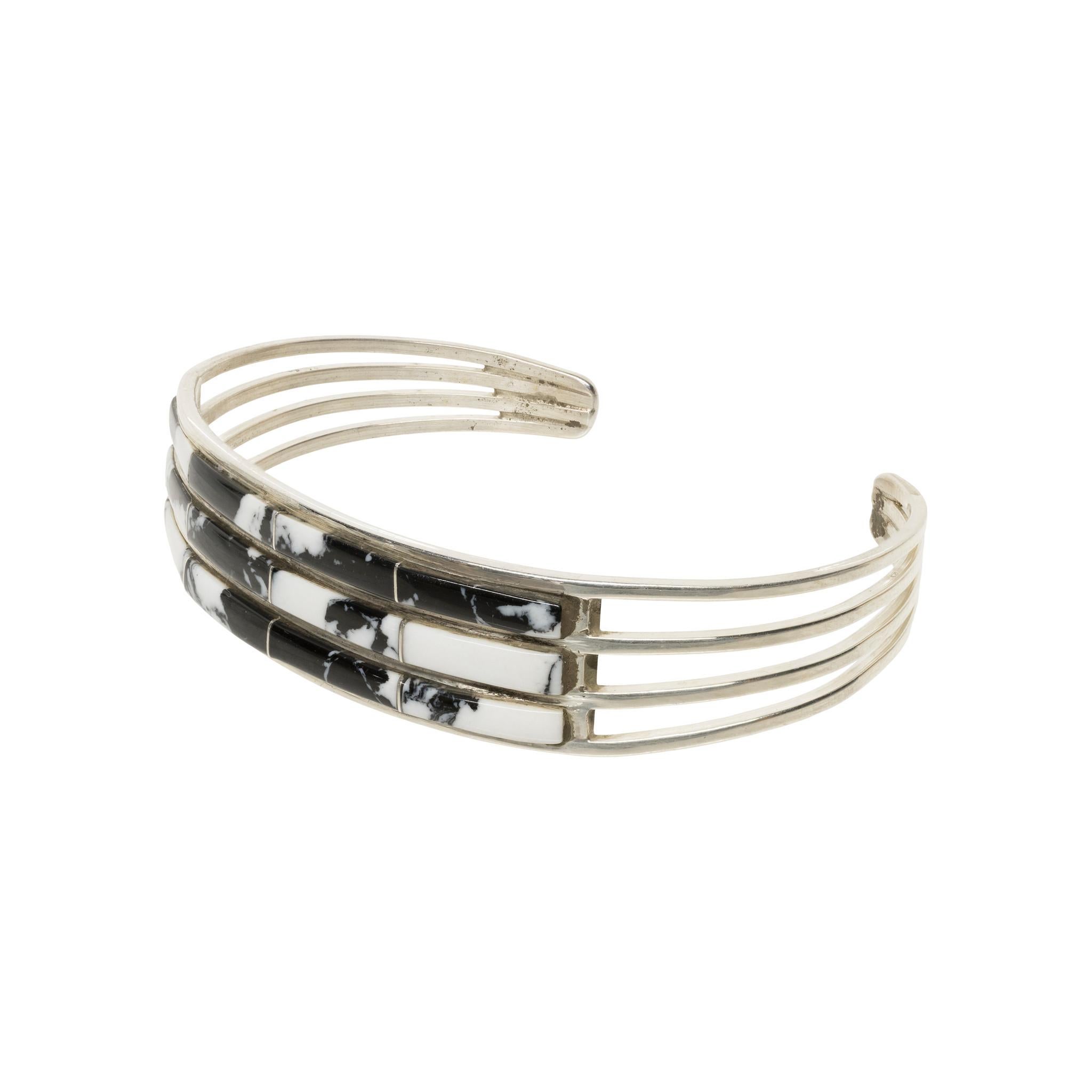 Navajo sterling silver and white buffalo turquoise bracelet by Navajo silversmith Jamie Johnson. Thin three layered design with four stones on each layer separated by sterling silver lines. Nice, polished look with open and merged band. Stamped