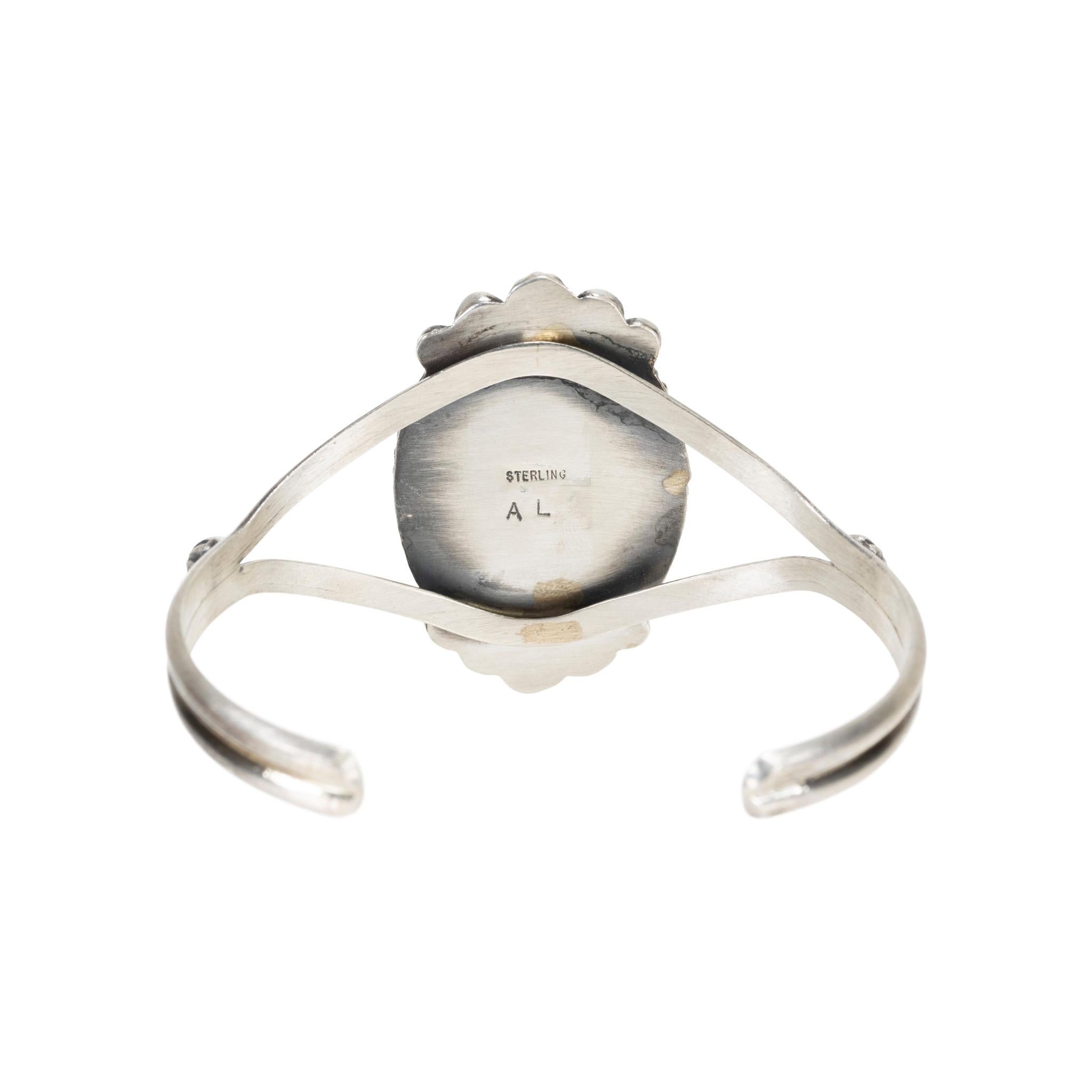 Navajo white buffalo turquoise and sterling bracelet. Large quality center stone surrounded by twisted rope border and palmettas. Maker's mark by Augustine Largo 