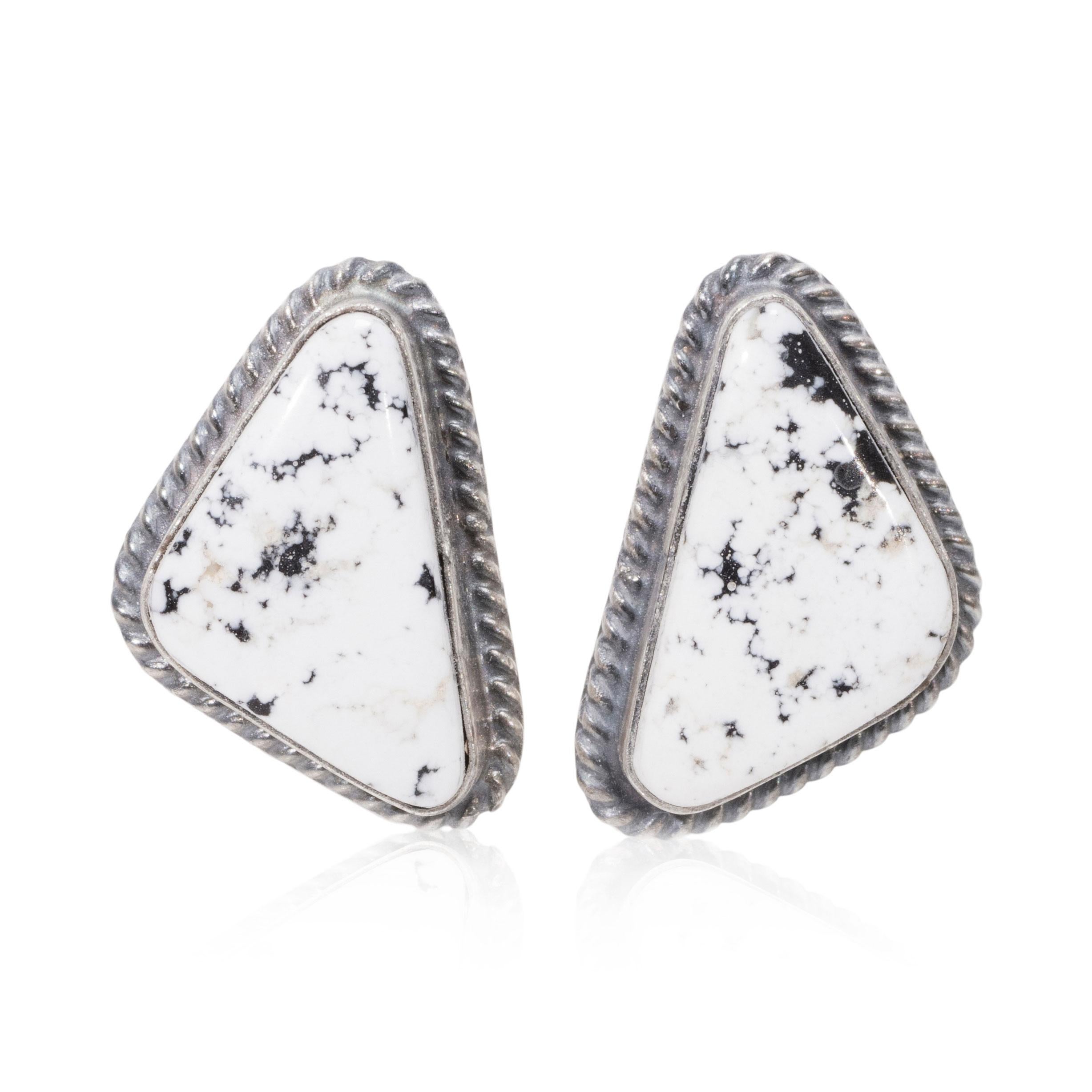 Navajo-Ohrstecker aus weißem Büffeltürkis und Sterlingsilber. Abgerundete, dreieckig geschliffene Steine mit strahlend weißer Farbe und minimaler schwarzer Matrix auf der Oberfläche des Steins. In glatter Lünettenfassung mit gedrehtem Seilrand.
