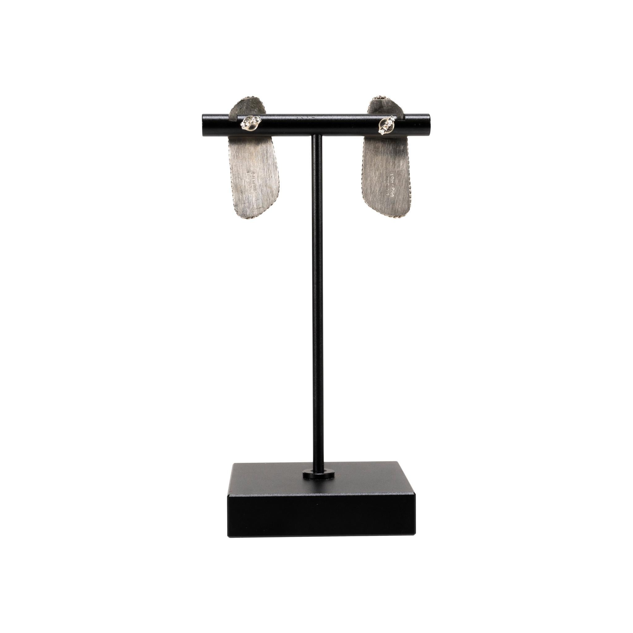 Orecchini a perno in turchese di bufalo bianco Navajo e argento sterling. Pietre rettangolari asimmetriche arrotondate con incastonatura a dente di sega e classico bordo in corda ritorta su montanti. Le pietre sono di un colore bianco intenso con