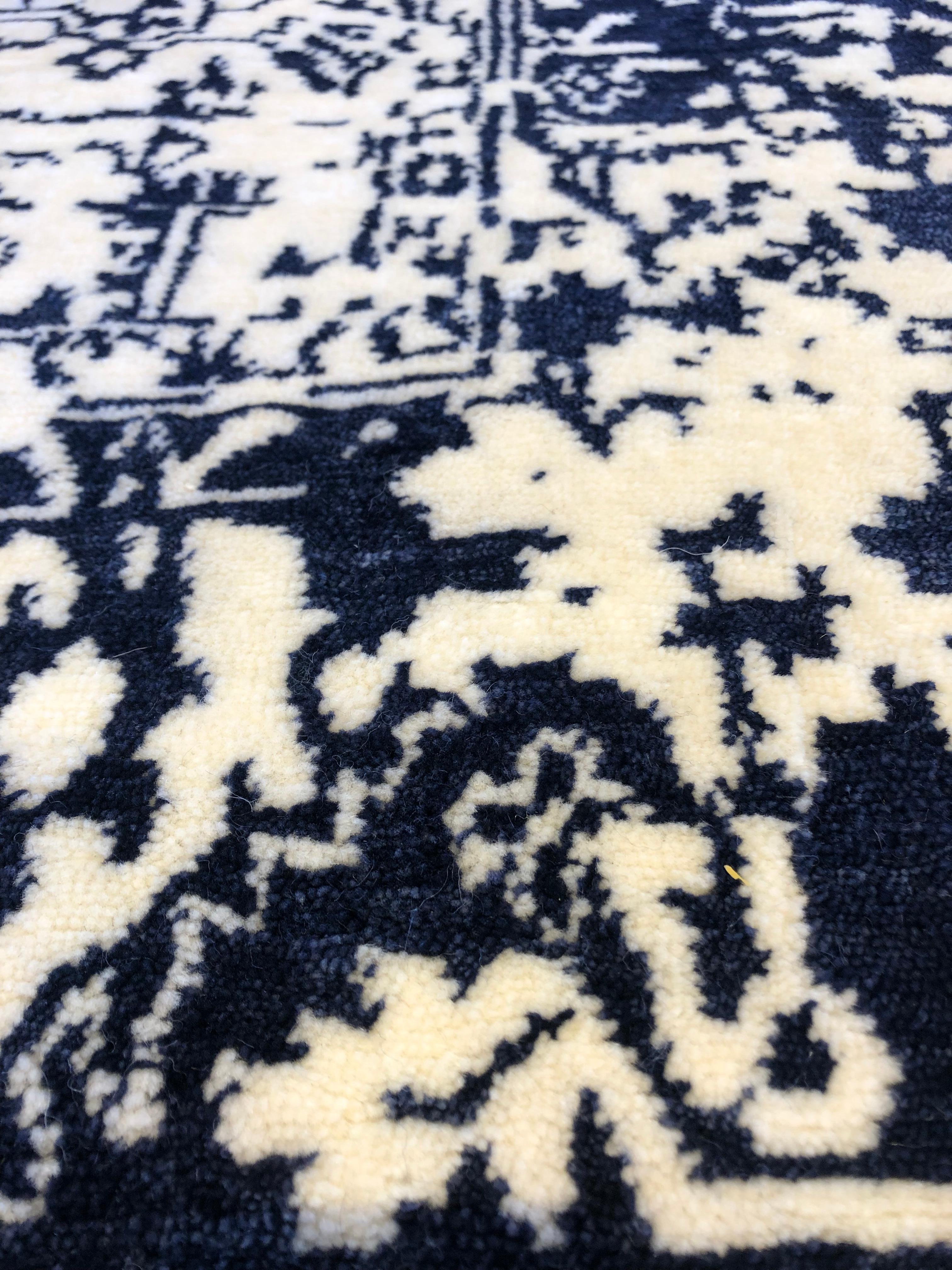Traditional elegance with a contemporary spin. Ivory center field surrounded by navy blue border. Wool. Hand made in India using vegetal dyes.