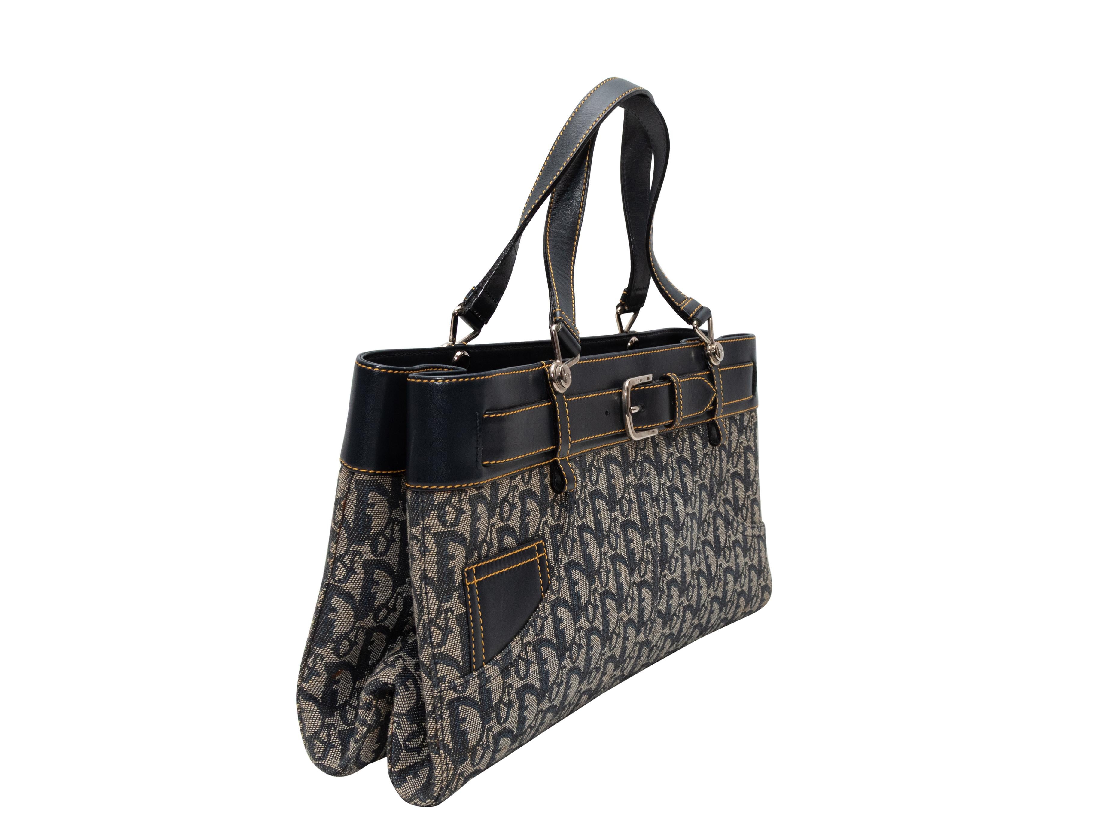 Navy & Beige Christian Dior Trotteur Oblique Handbag. The Trotteur Oblique Handbag features a canvas body, leather trim, contrast stitching throughout, silver-tone hardware, a front buckle accent, dual top handles, and a top zip closure. 15