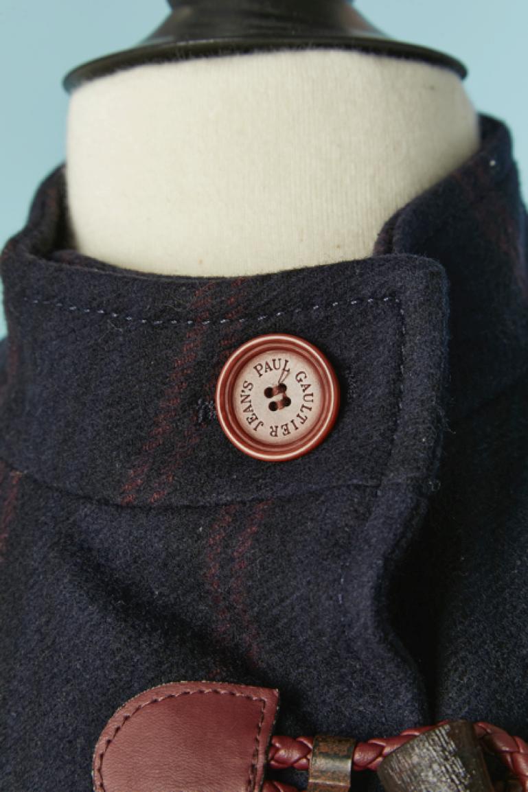 Duffle-coat en laine rayée bleu marine et bordeaux, légèrement paddé. Composition du tissu principal : 90% laine, 10% nylon. Doublure et garniture en polyester.
Fermeture par boutons et boutonnières sur le milieu du devant. Poches sur les deux