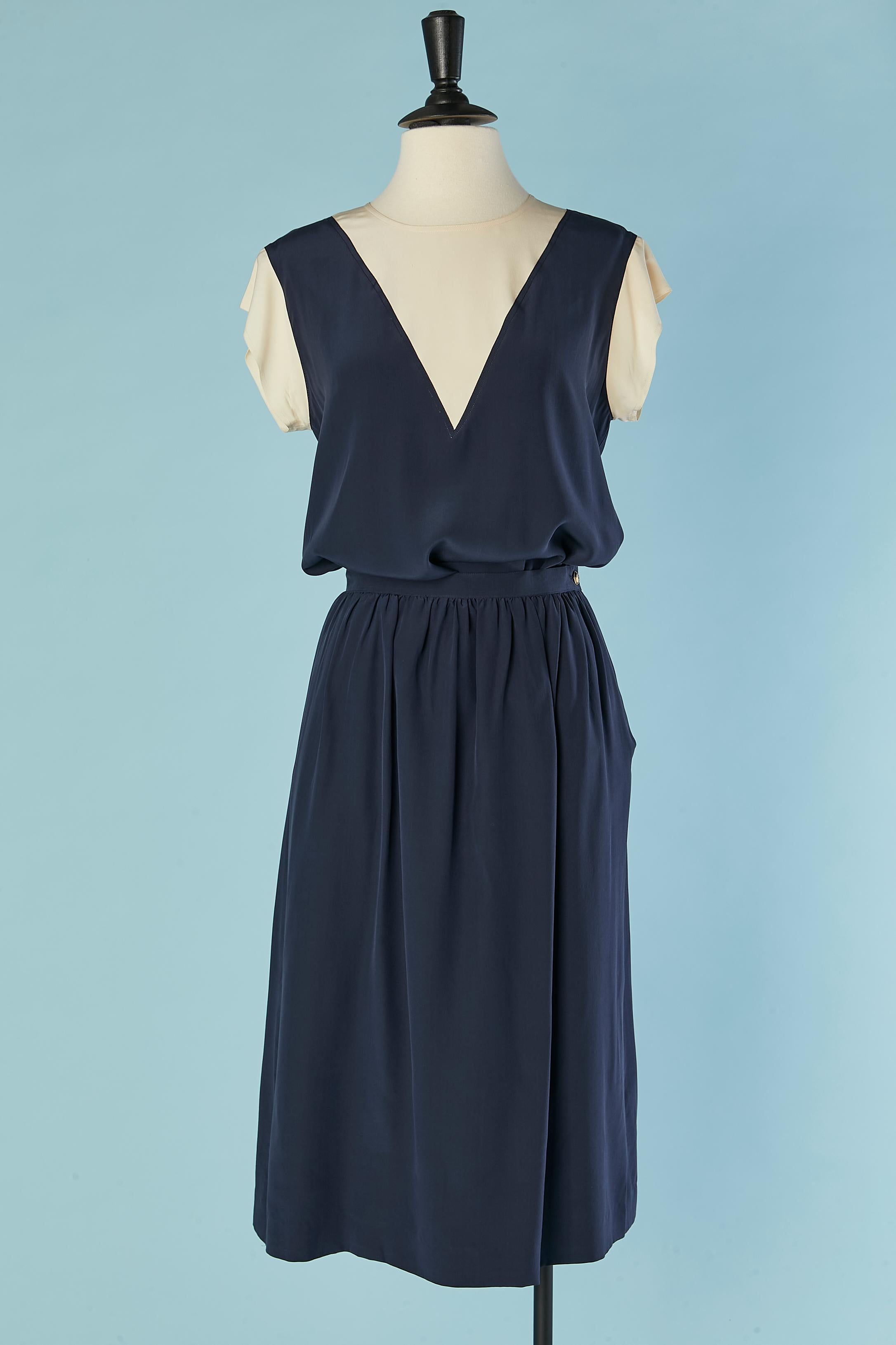 Ensemble en soie bleu marine et ivoire. 
Boutons de marque en nacre au milieu du dos sur le dessus. Fermeture de la jupe par un bouton en métal doré. 
Taille 36 sur l'étiquette pour le haut mais s'adapte plus probablement 38 / M 
La jupe est
