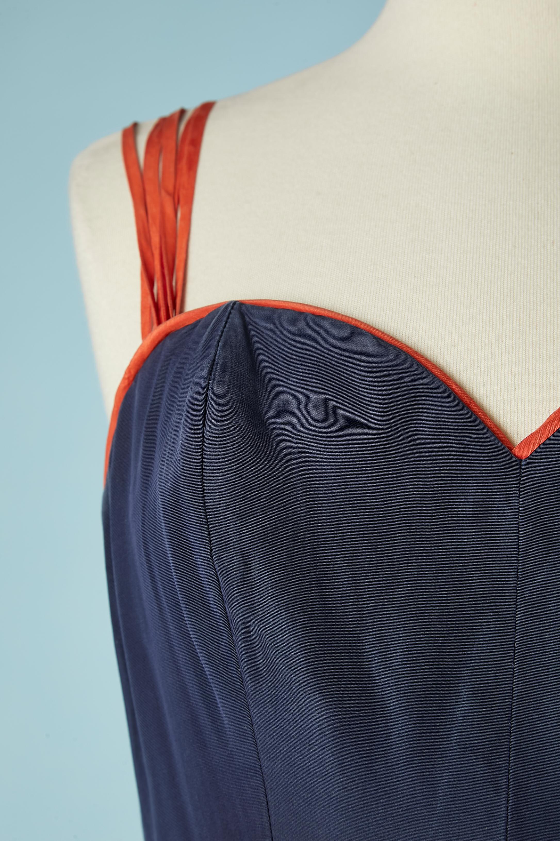 Navy blue Faille( silk textile) bustier dress with orange bow in the same fabric. Orange piping on the edge of the bustier. Stiff organza lining and synthetique horsehair in the bottom edge inside ( to keep the bottom edge wavy) Double zip in the