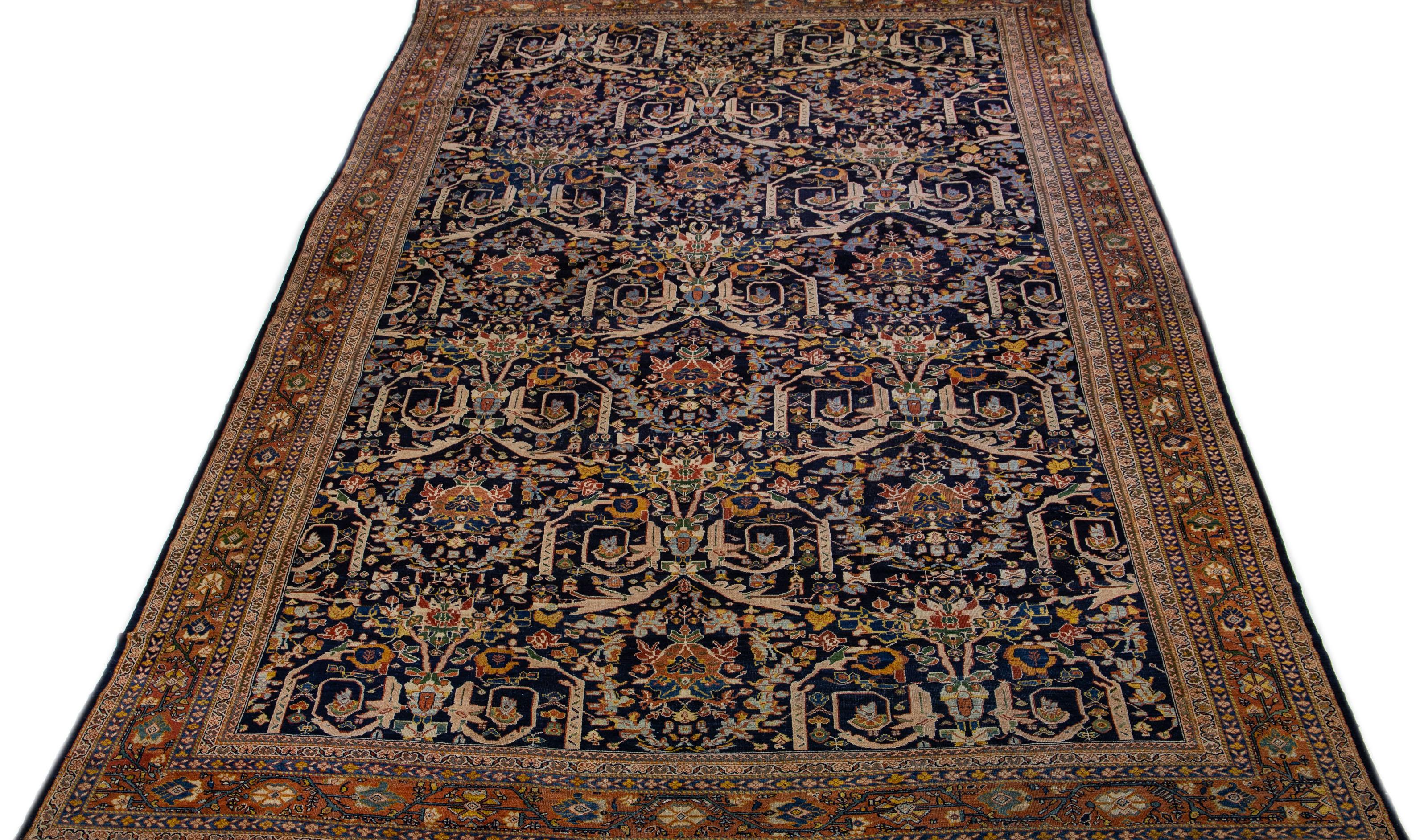 A stunning antique mahal wool rug, exquisitely hand-knotted and endowed with a mesmerizing navy blue color field. This Persian masterpiece showcases a rusted designed frame that encases an all-over floral pattern, beautifully accentuated with