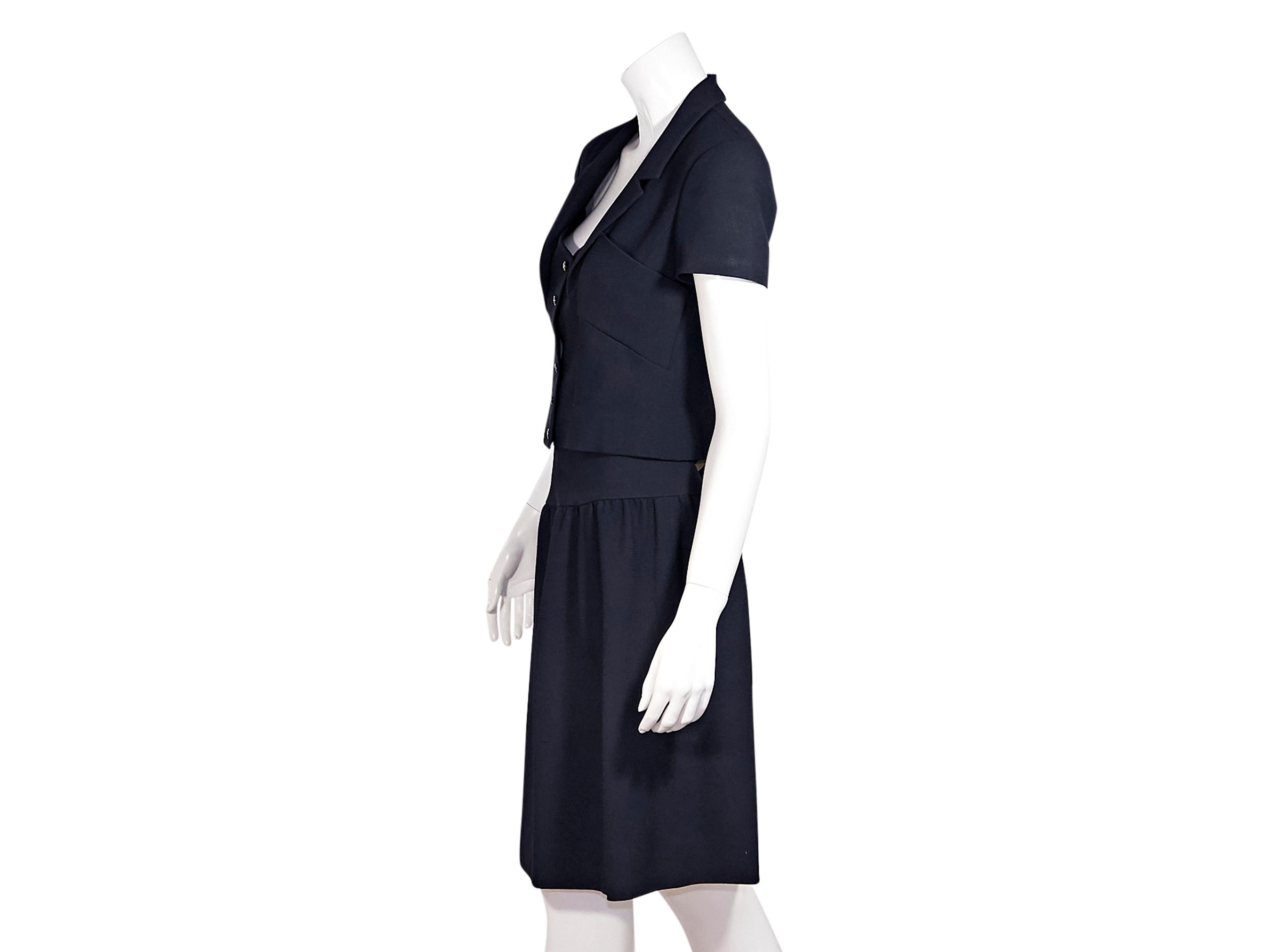 Product details:  Navy blue skirt suit set by Chanel.  From 1995.  Cropped jacket.  Notched lapel.  Short sleeves.  Button-front closure.  Seams create a fitted silhouette.  Matching skirt.  Banded waist.  Concealed zip closure.  Jacket:  30