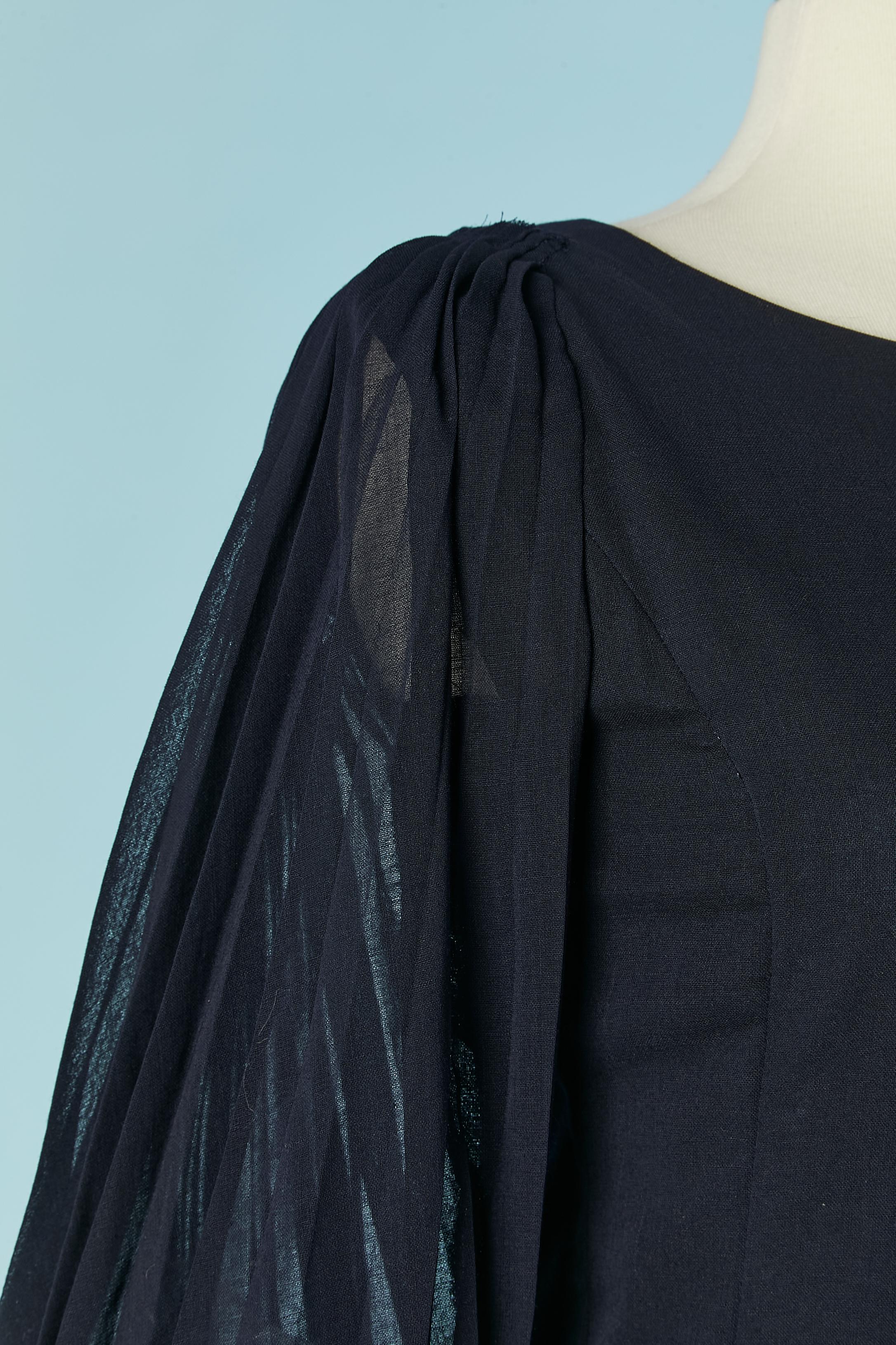 Navy blue dress with sunray pleated see-through sleeves. Lining in the same fabric with button and buttonhole closure on the middle back. Button and buttonhole on the cuffs as well. No fabric tag composition but probably wool crepe. Zip closure on