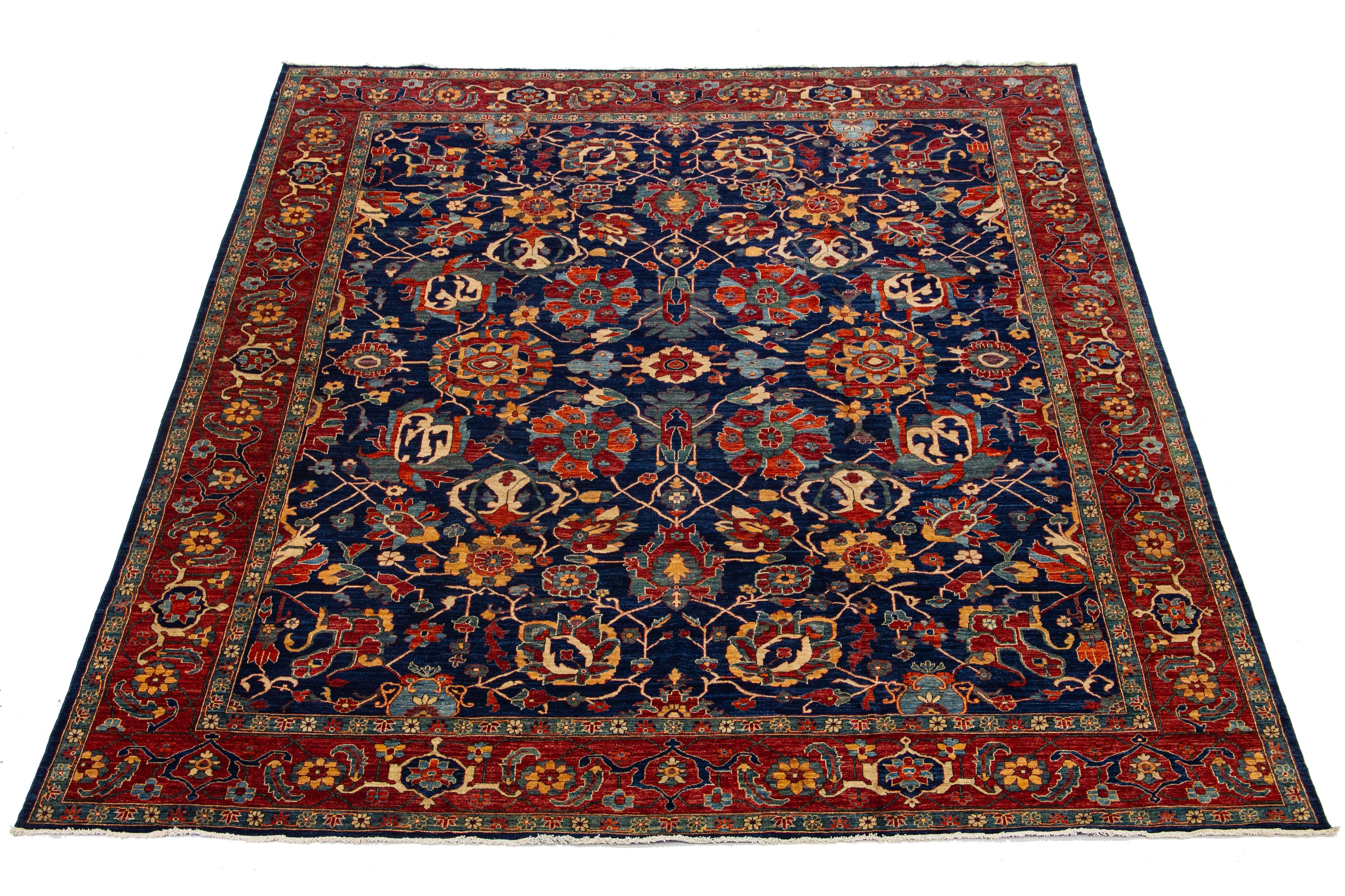 Il s'agit d'un superbe tapis en laine nouée à la main, de style Serapi, avec un champ de couleur bleu marine. La pièce présente un cadre au design complexe et un motif floral époustouflant avec d'exquises touches multicolores.

Ce tapis mesure