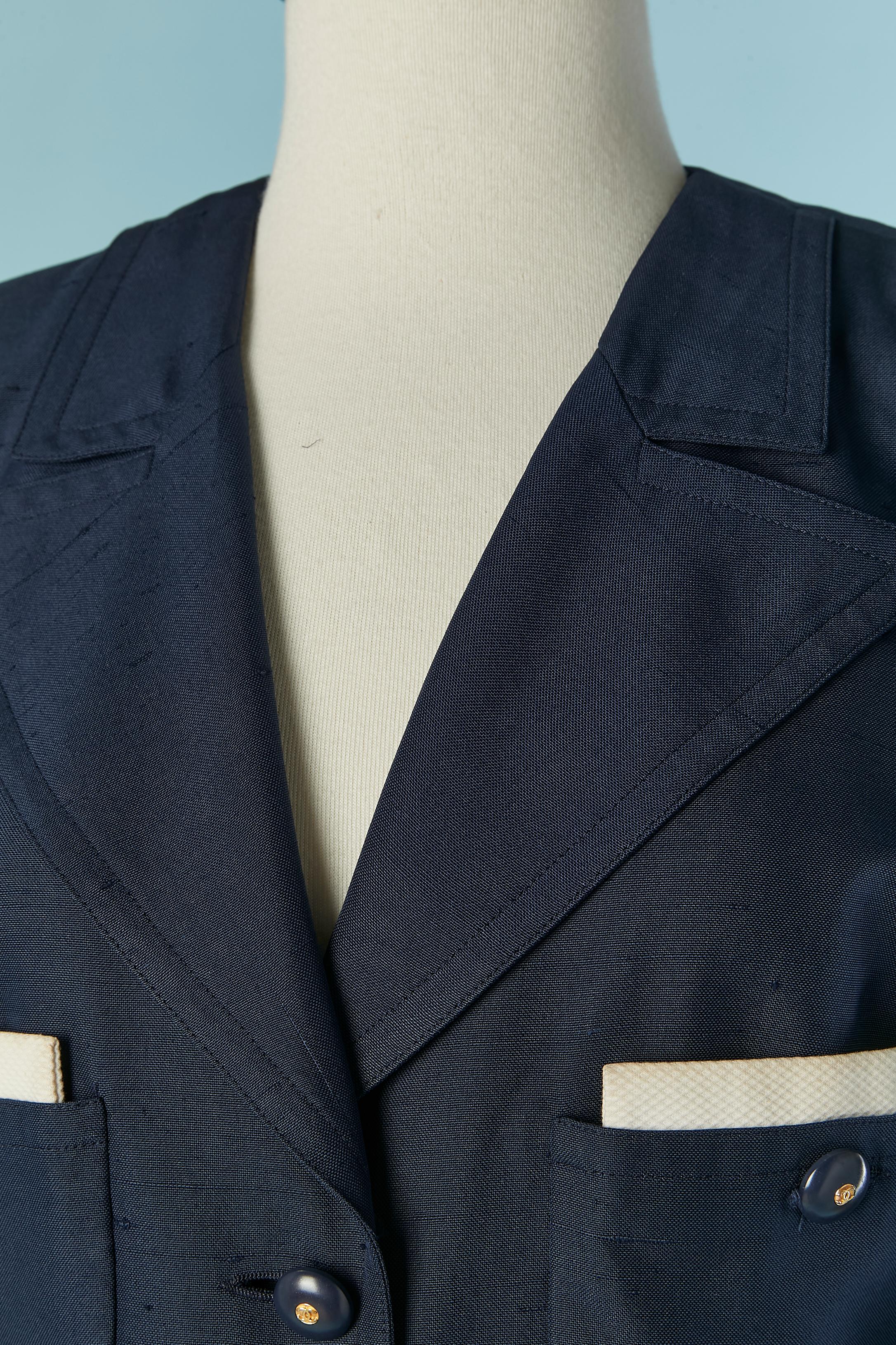 Traje de falda de seda cruda azul marino con detalles de Piqué de algodón blanco. Forro de marca de seda. Botón con la marca y cierre de ojal en la parte delantera central , en el bolsillo y en los puños. 
TALLA DE LA CHAQUETA : 38 (fR) M 
TALLA DE