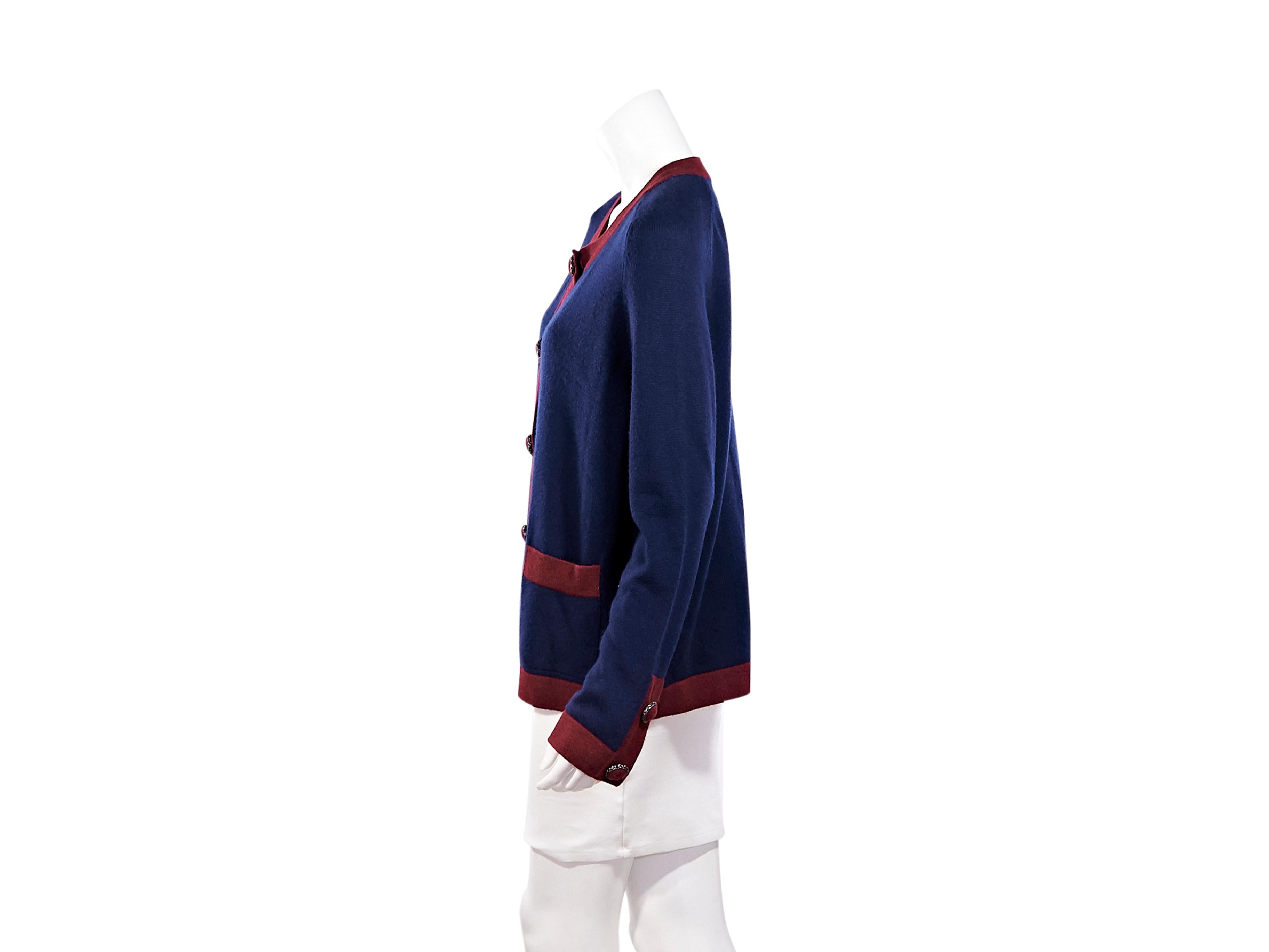 Product details:  Navy blue and red cashmere cardigan by Chanel.  Roundneck.  Long sleeves.  Button-front closure.  Waist patch pockets.  Label size FR 50.  46
