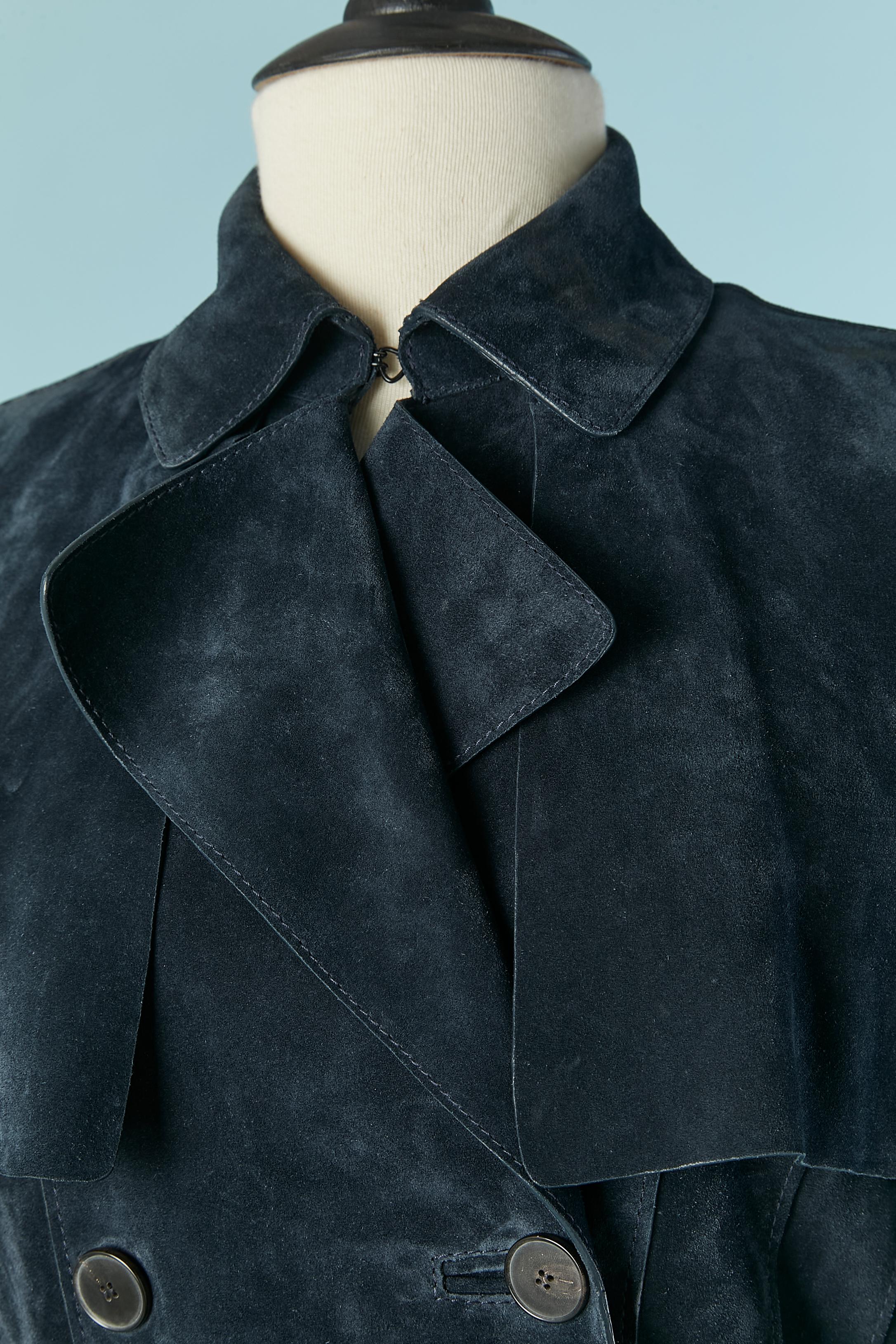 Marineblauer Trenchcoat aus Wildleder, der bis zu den Hüften zusammengenäht und dann geöffnet ist.  Wildledergürtel, Schnalle und Gürtelschlaufe. Tasche auf beiden Seiten. 
Kein Futter. Knopf und Knopfverschluss an der mittleren Schrift + an den