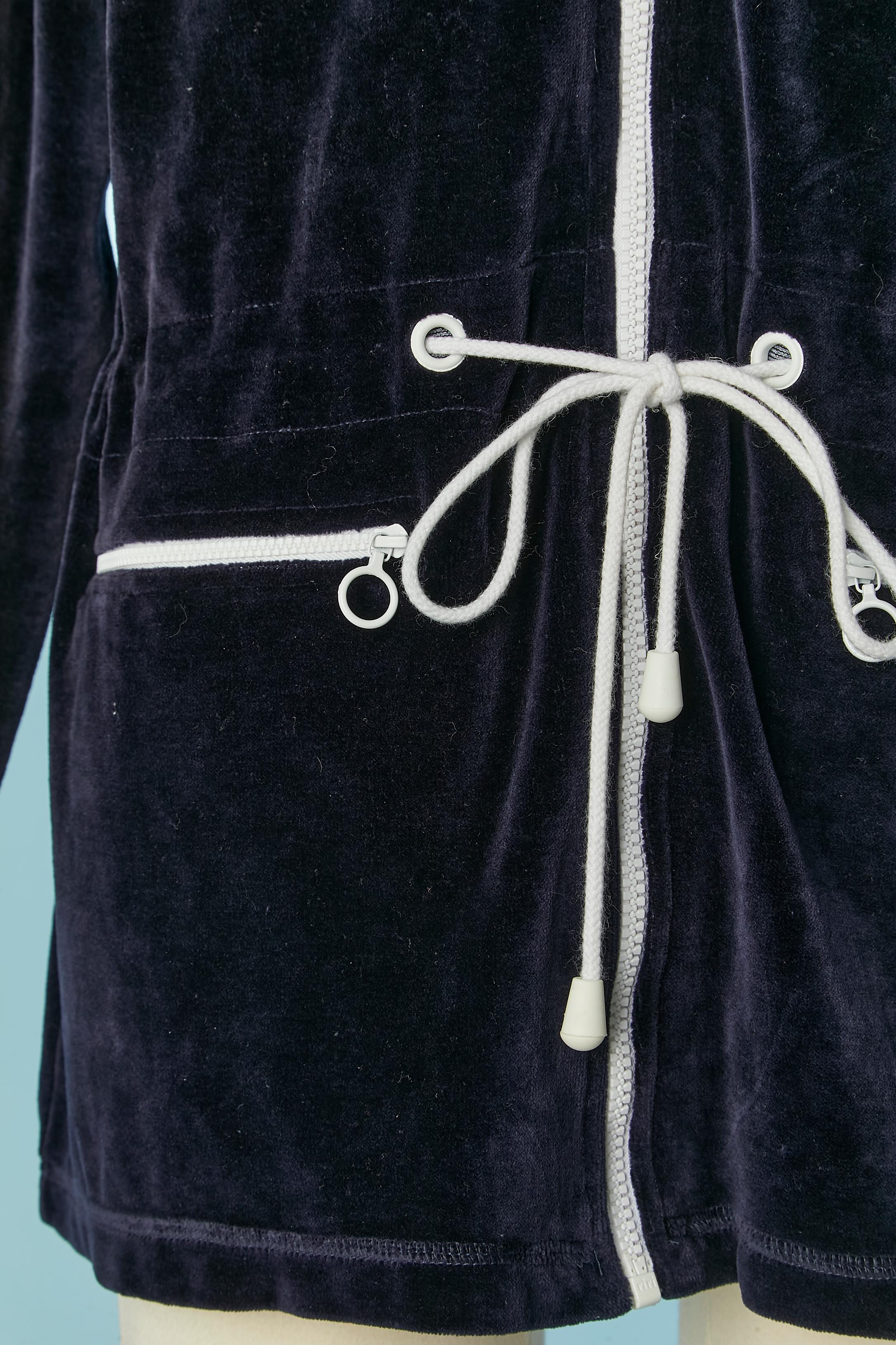 Giacca in velluto blu navy con cappuccio e zip bianca. Composizione della Fabrice: 80% cotone, 20% poliestere. Coulisse in vita. Tasca su entrambi i lati + una tasca sul petto sinistro con chiusura a zip. 
TAGLIA L 