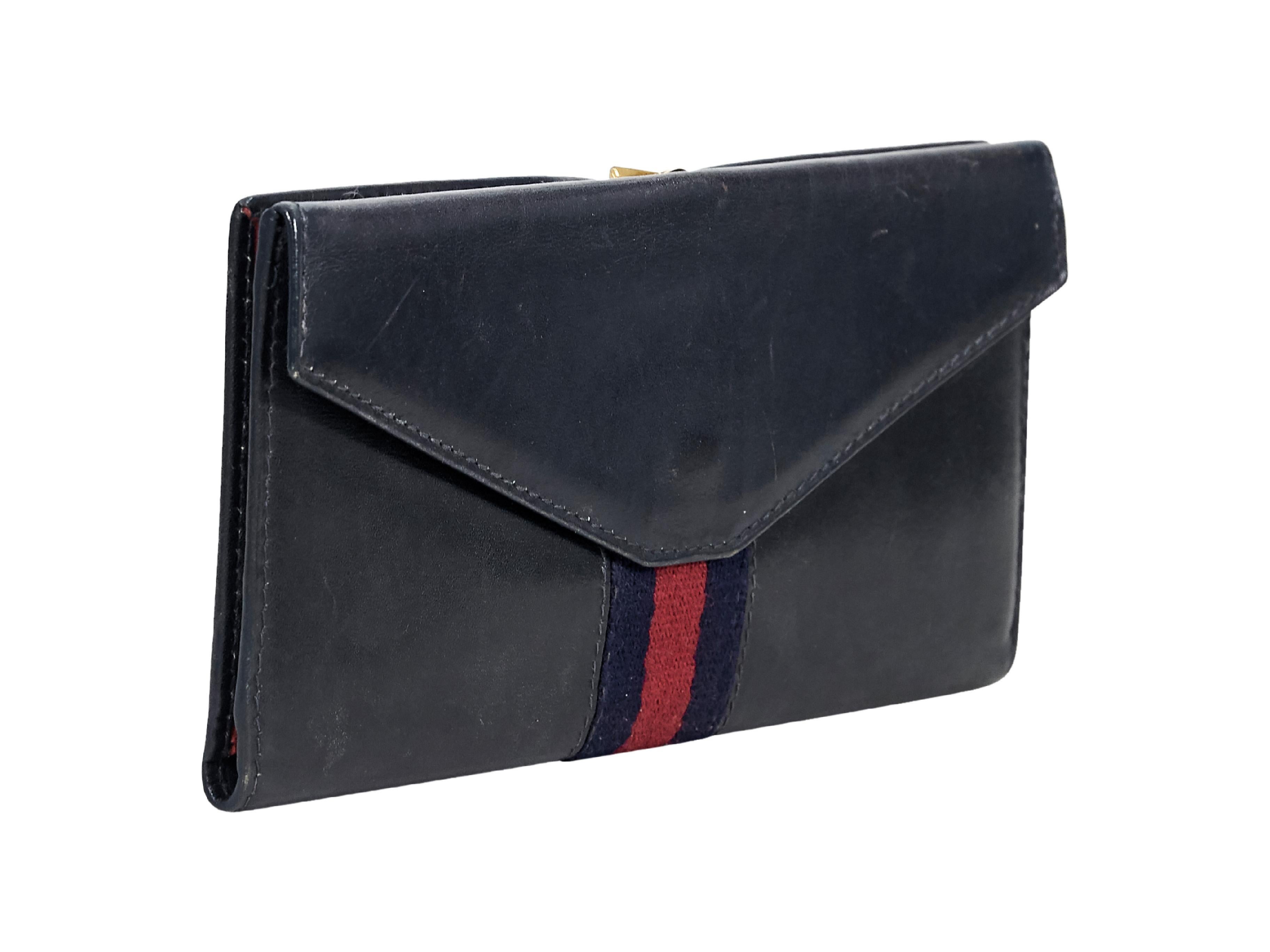 Product details:  Vintage navy blue leather wallet by Gucci.  Striped canvas accent.  Top flip-lock closure.  Red saffiano leather lined interior with inner slide pockets.  Front snap flap coin pouch.  Goldtone hardware.  7
