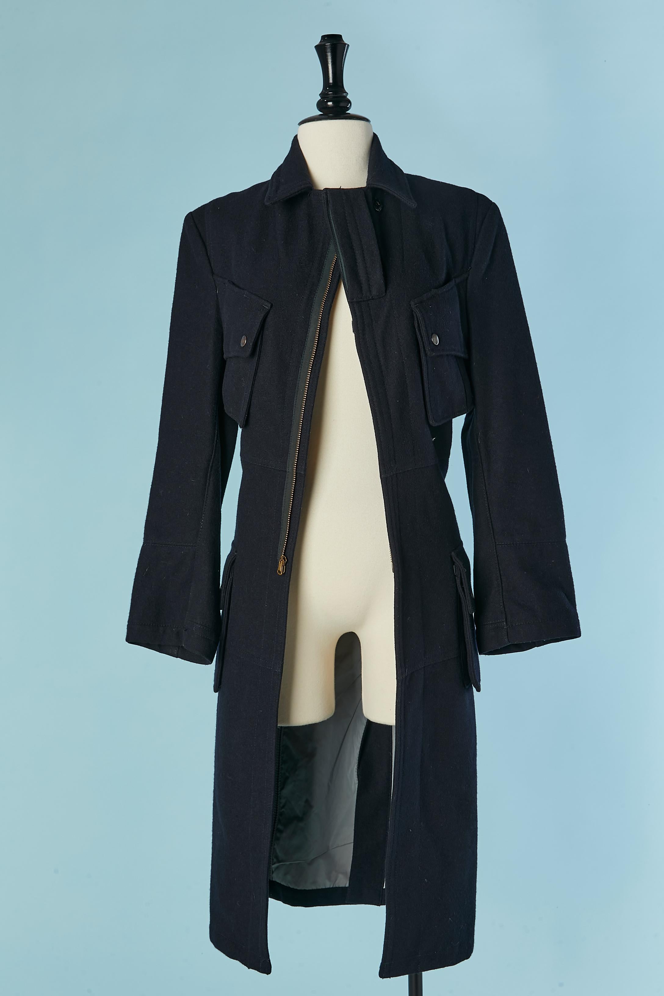 Cappotto in lana blu navy. Composizione del tessuto principale: 90% lana, 10% nylon. Composizione della fodera: 55% poliestere, 45% cotone. 
Chiusura con zip al centro della fronte + un bottone a pressione sul colletto e un gancio sul davanti. Tasca