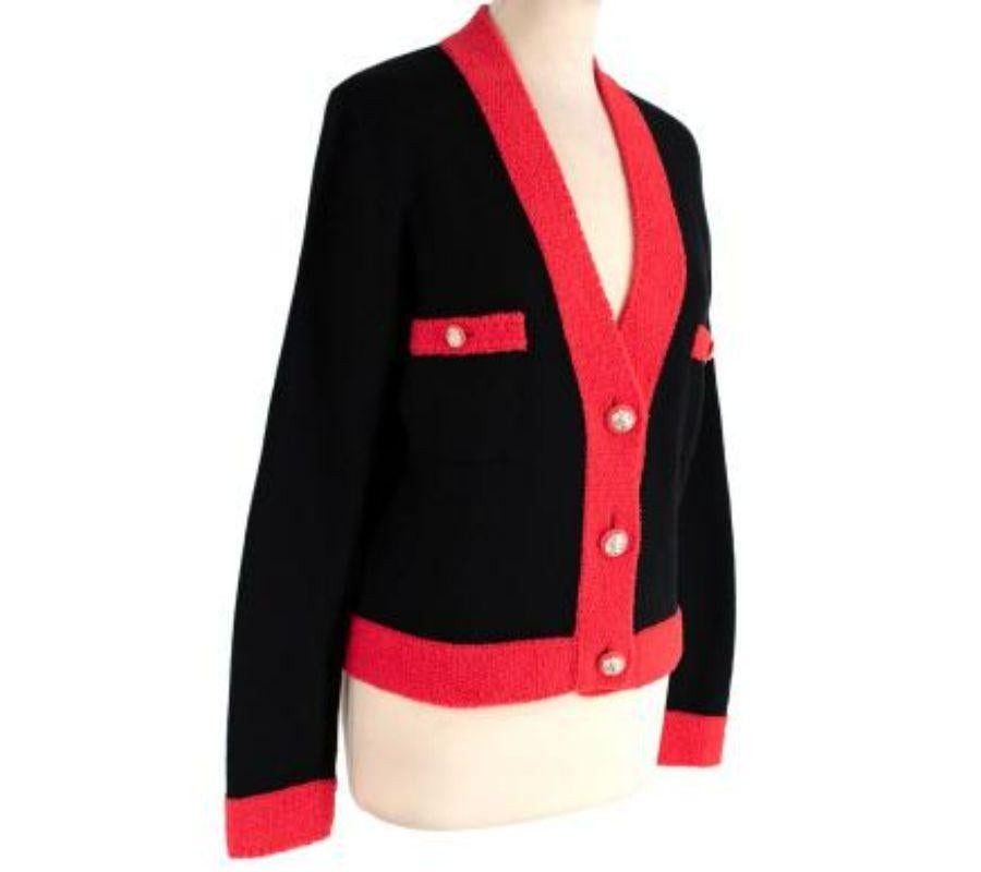 Chanel black cashmere red teddy trim cardigan
 
 - Hip length, sumptuous cashmere cardigan in black with a contrasting teddy-feel red trim
 - Lions head buttons 
 - 2 inset breast pockets 
 
 Materials:
 73% Cashmere 
 19% Wool 
 8% Polyamide 
 

