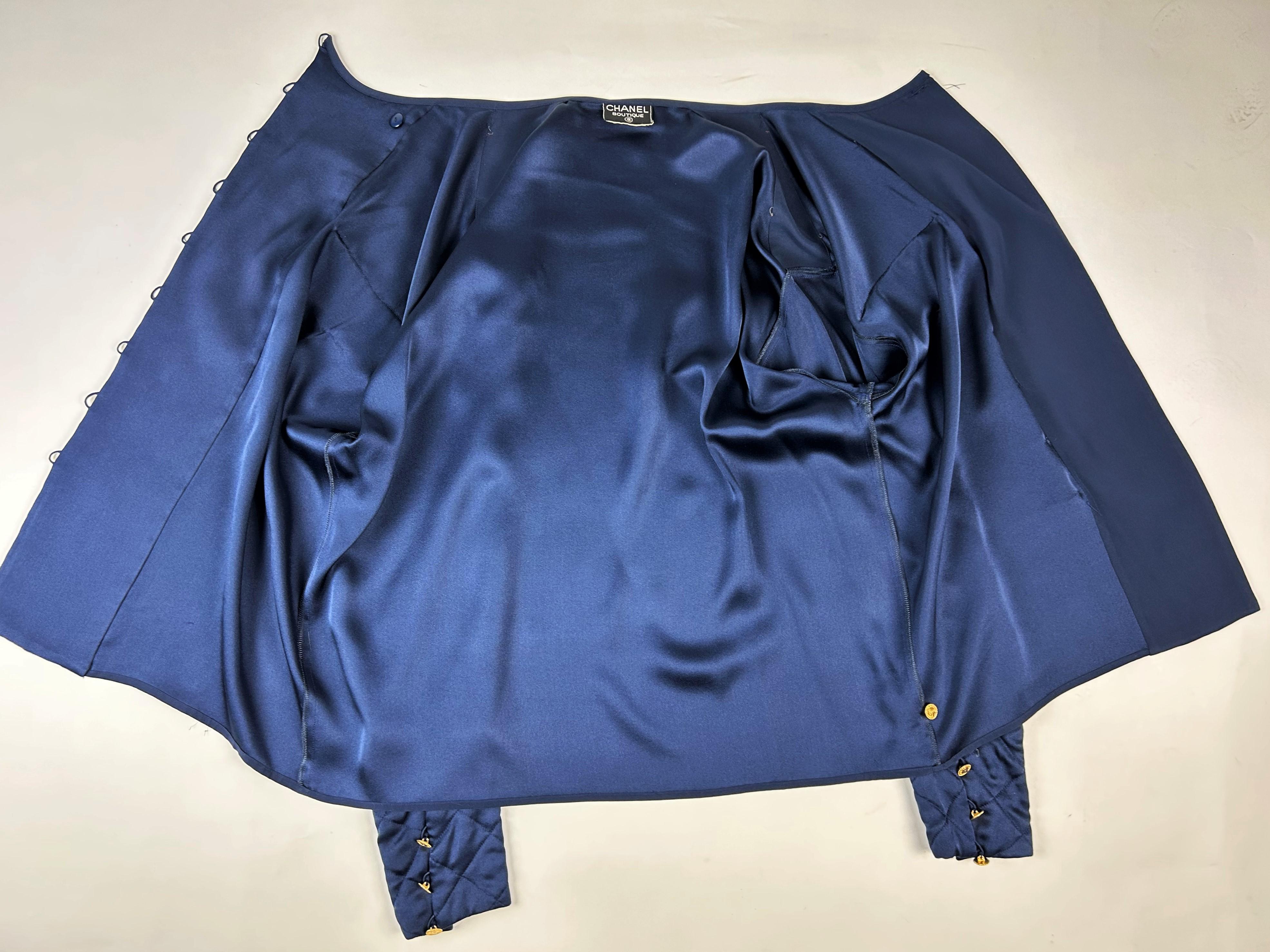 Circa 1995

France

Navy crepe blouse from Chanel Boutique dating from the Lagerfeld years when he was head of this famous House. Loose, flowing blouse with cross-buttoning. Complete with 19 gold metal buttons with the Coco Chanel logo, Paris