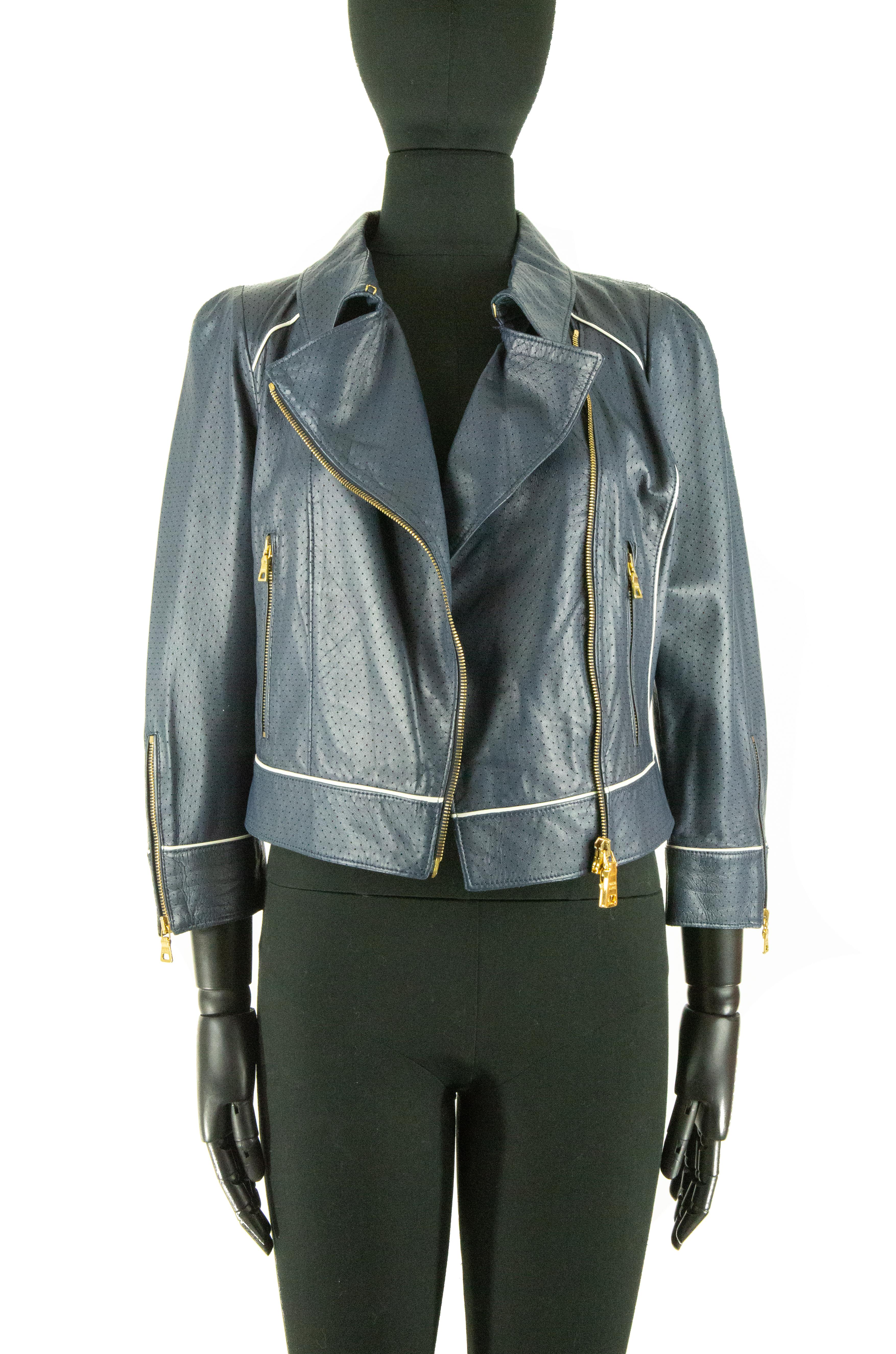 A navy Prada cropped leather jacket. This jacket features gold-coloured zippers; the main zipper working its way asymmetrically from the left shoulder down to the hem of the jacket. It has four more zippers; two on the pockets at the front, the