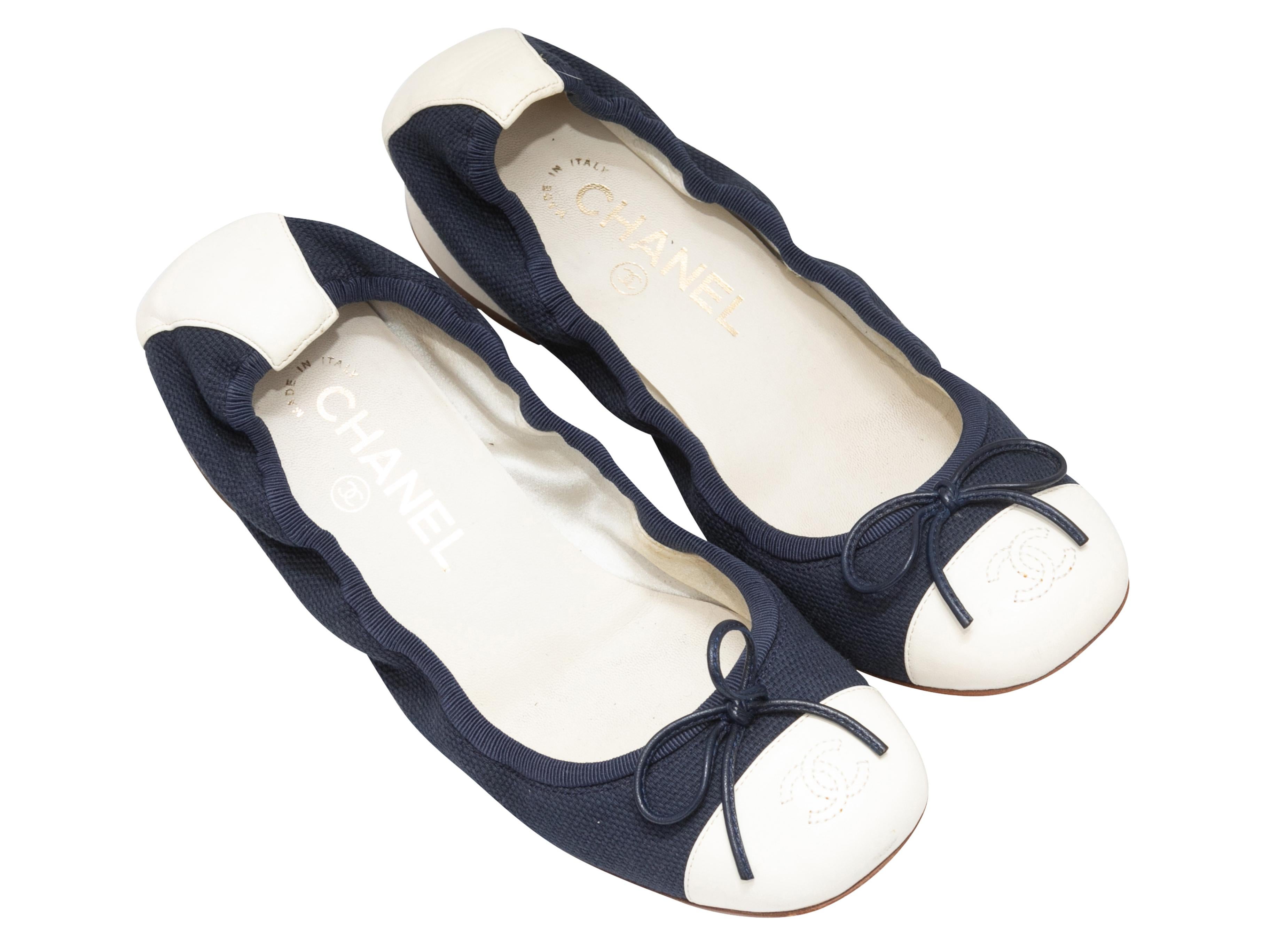 Navy canvas and white leather cap-toe low block heel pumps by Chanel. CC logo embroidery and bow accents at tops. 1.25