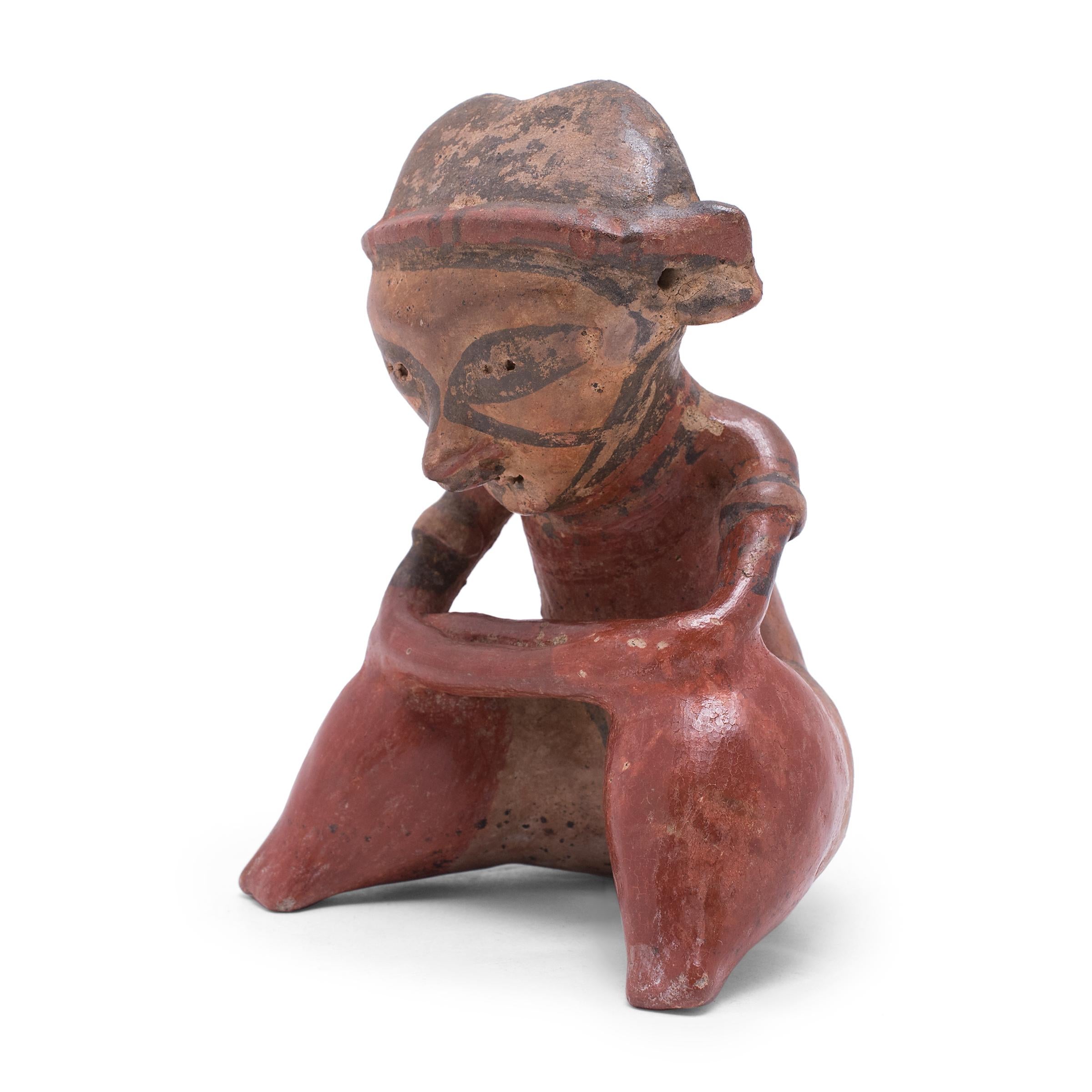 This seated ceramic figure is attributed to the ancient Nayarit region of Mexico and was likely used as a ritual or burial offering. The ceramic works of this style, known as Chinesco figures, are often distinguished by puffy, slit-like eyes blended