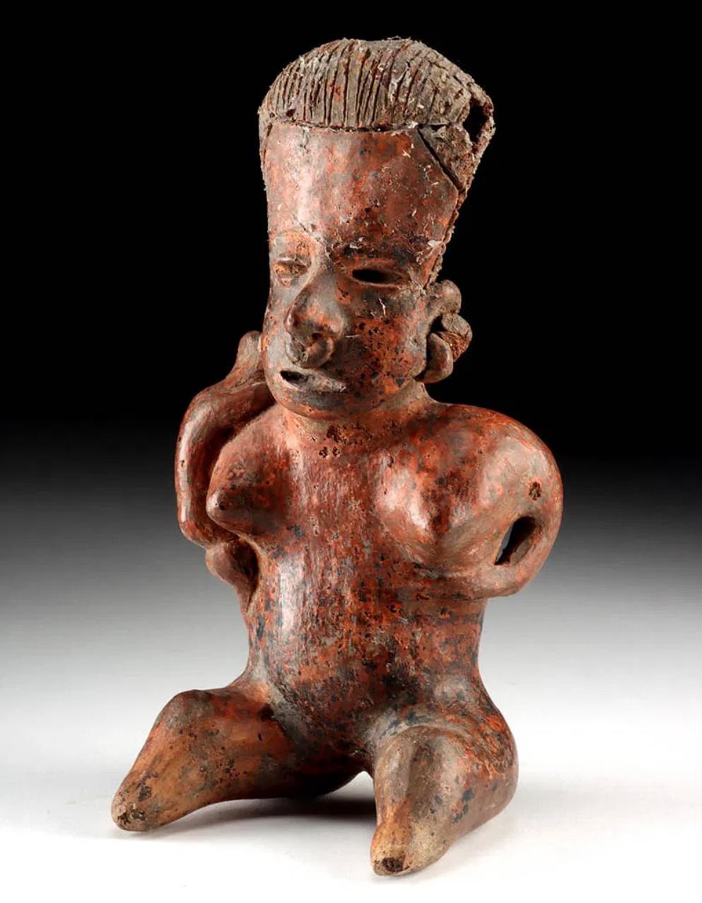 Nayarit Fertility Figure féminine avec enfant
Pre-Columbian, Mexique occidental, Nayarit, 
Ca. 300 BCE à 300 CE. 
Figure féminine assise en terre cuite, issue de la tradition des tombes à puits, portant un nourrisson.  sur son épaule droite -