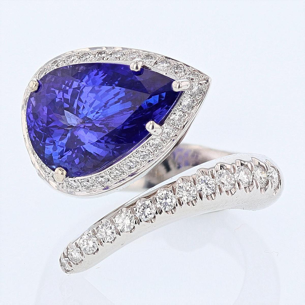This ring is designed by Nazarelle and made in 14 karat white gold. The center stone is a pear shape tanzanite weighing 7.10 carats and is prong set. The mounting features 59 round cut diamonds weighing 0.88 carats.