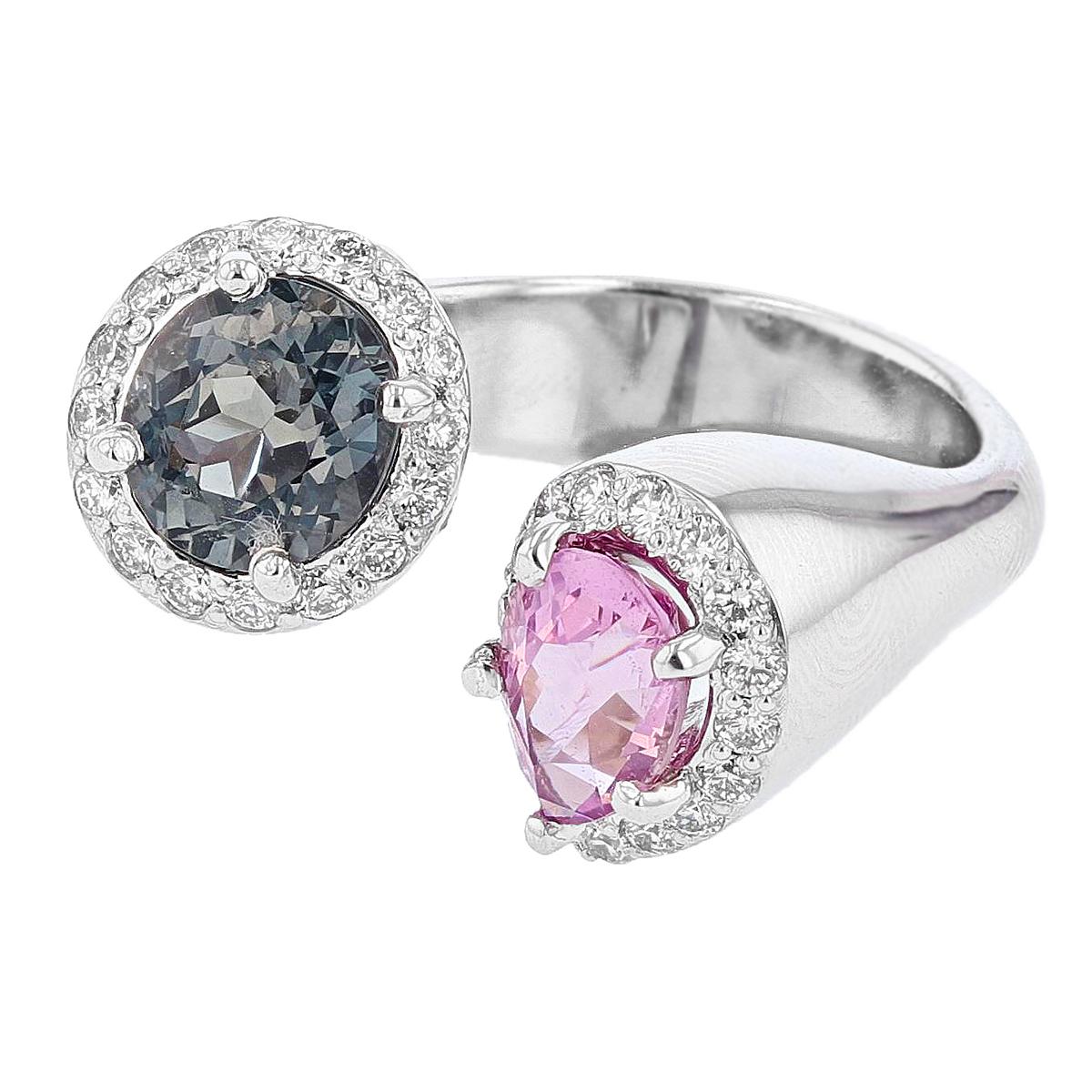 This ring is designed by Nazarelle and made in 14k white gold. The center stones are an oval blue spinel and a pear shape pink spinel weighing 2.91 total carat weight and they are prong set. The mounting features 33 round diamonds weighing 0.51ct.