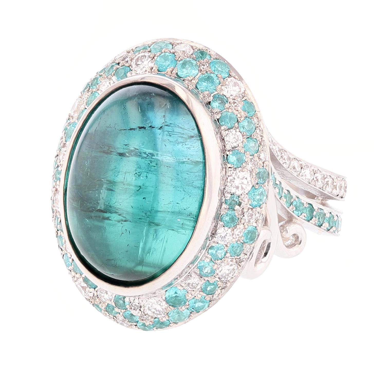 This ring is designed by Nazarelle and made in 14k white gold. For the center stone it features one cabochon oval blue tourmaline weighing 11.50ct and bezel set. The mounting features 87 pave set round shape paraiba tourmalines weighing 1.20ct and