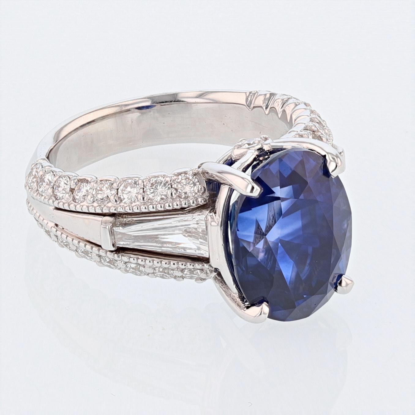This ring is made in 18k white gold and features a GRS certified 7.28ct oval cut blue sapphire. The certificate number is GRS2014-037576. The ring also features 2 bezel set tapered baguettes weighing 0.38ct with color grade (G) and clarity grade