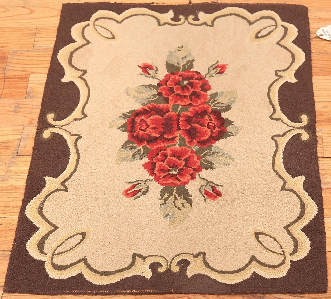 Antique American small size and floral design hooked rug, origin: America, circa early 20th century. Size: 2 ft. 1 in x 2 ft. 10 in (0.63 m x 0.86 m). A spray of roses hovers amidst a tan field surrounded by a scrolling cartouche and an outer zone