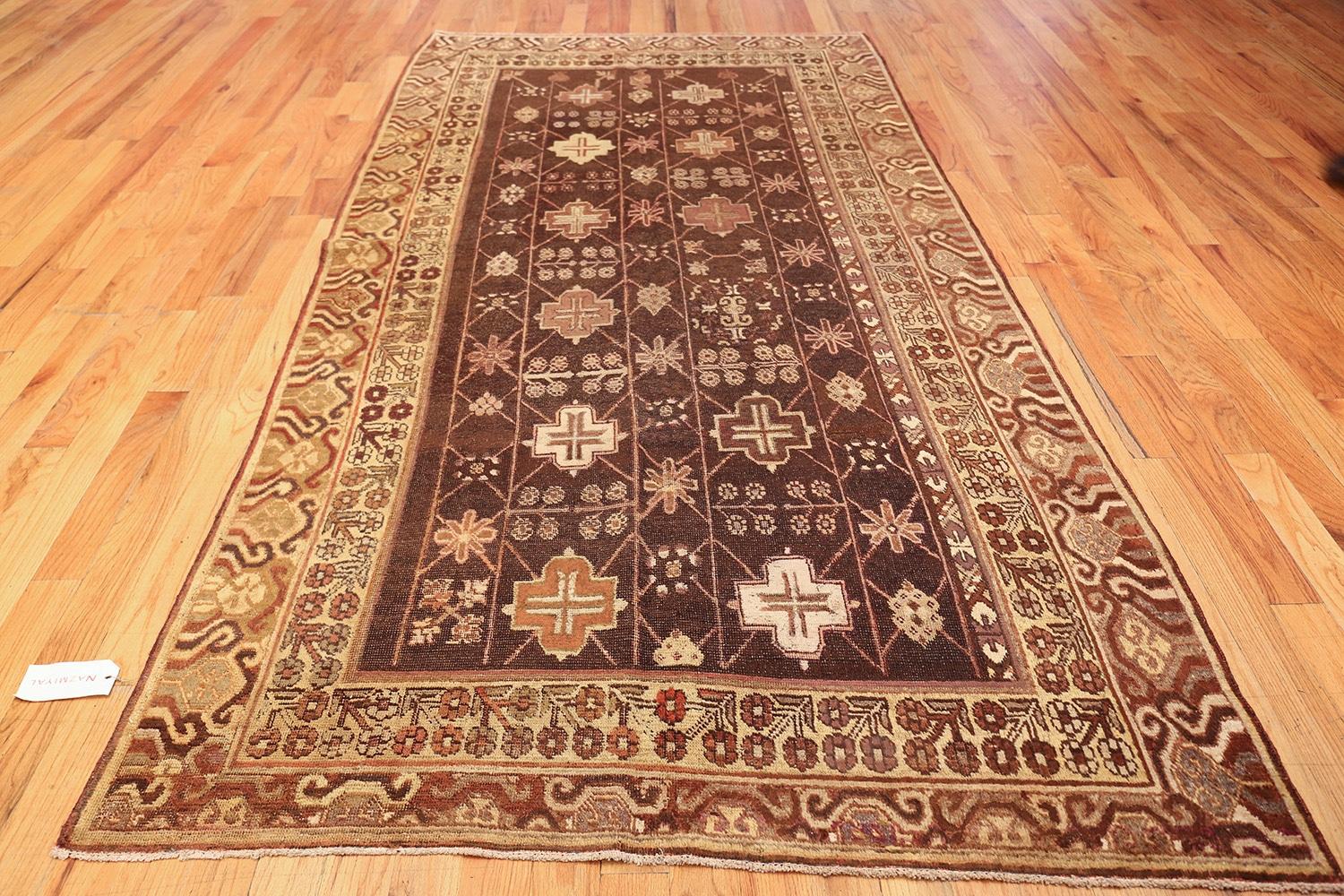 Brown Tribal and Geometric Antique Khotan Rug, Origin: East Turkestan, Circa: 1900 – Though produced along the Silk Road just to the west of China and Tibet, antique Khotan rugs like this reflect the design of Middle Eastern carpets as well. Her the