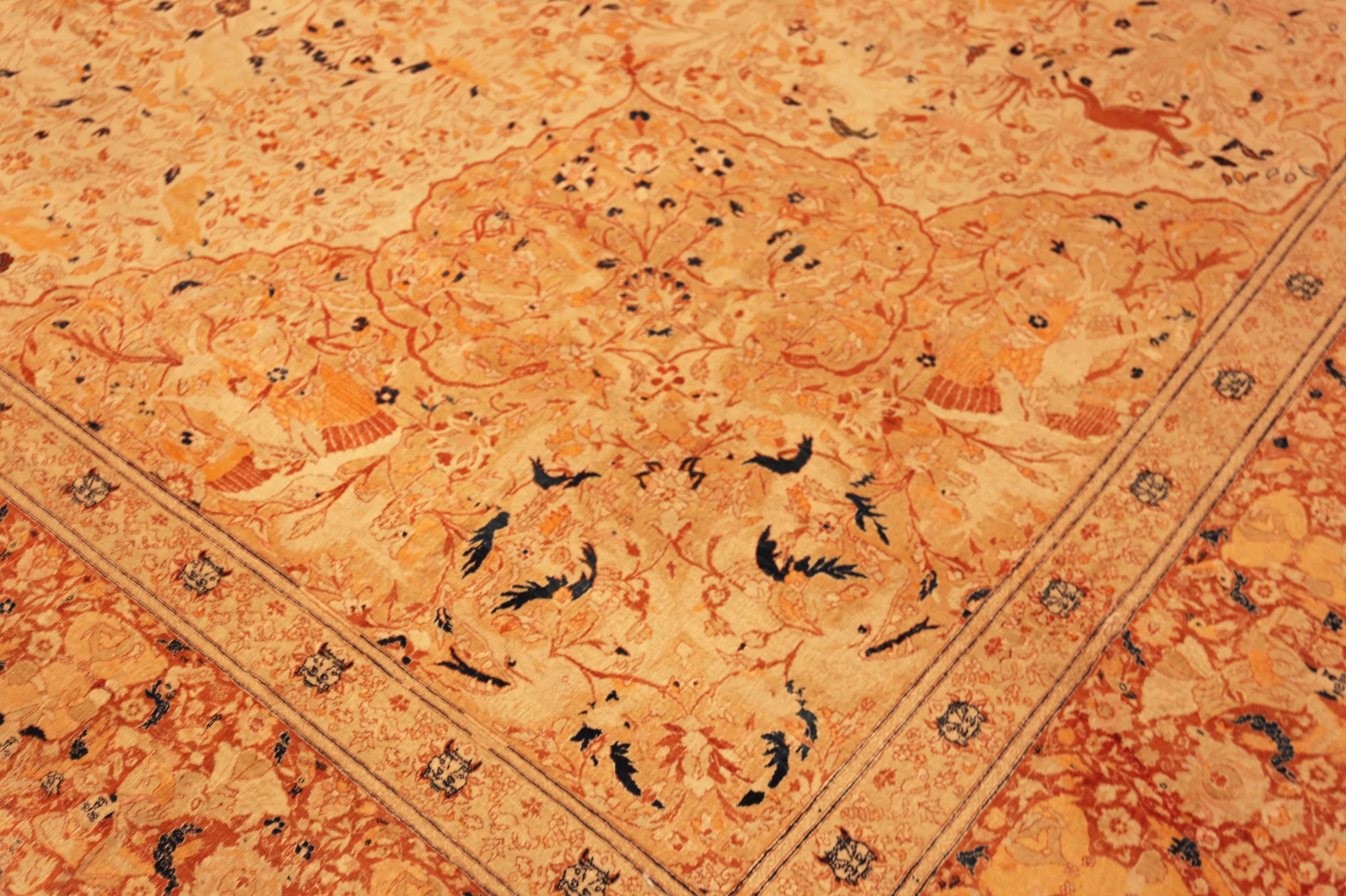 Der antike Tabriz-Jagdteppich zeigt eine lebendige Jagdszene mit Reitern, Tieren und botanischen Motiven.