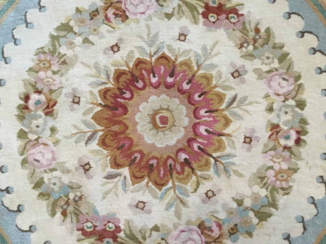 A lovely Collection 8 ft round wool knotted Aubusson style area rug in light green, red oxide, terracotta, brown, light blue and yellow.