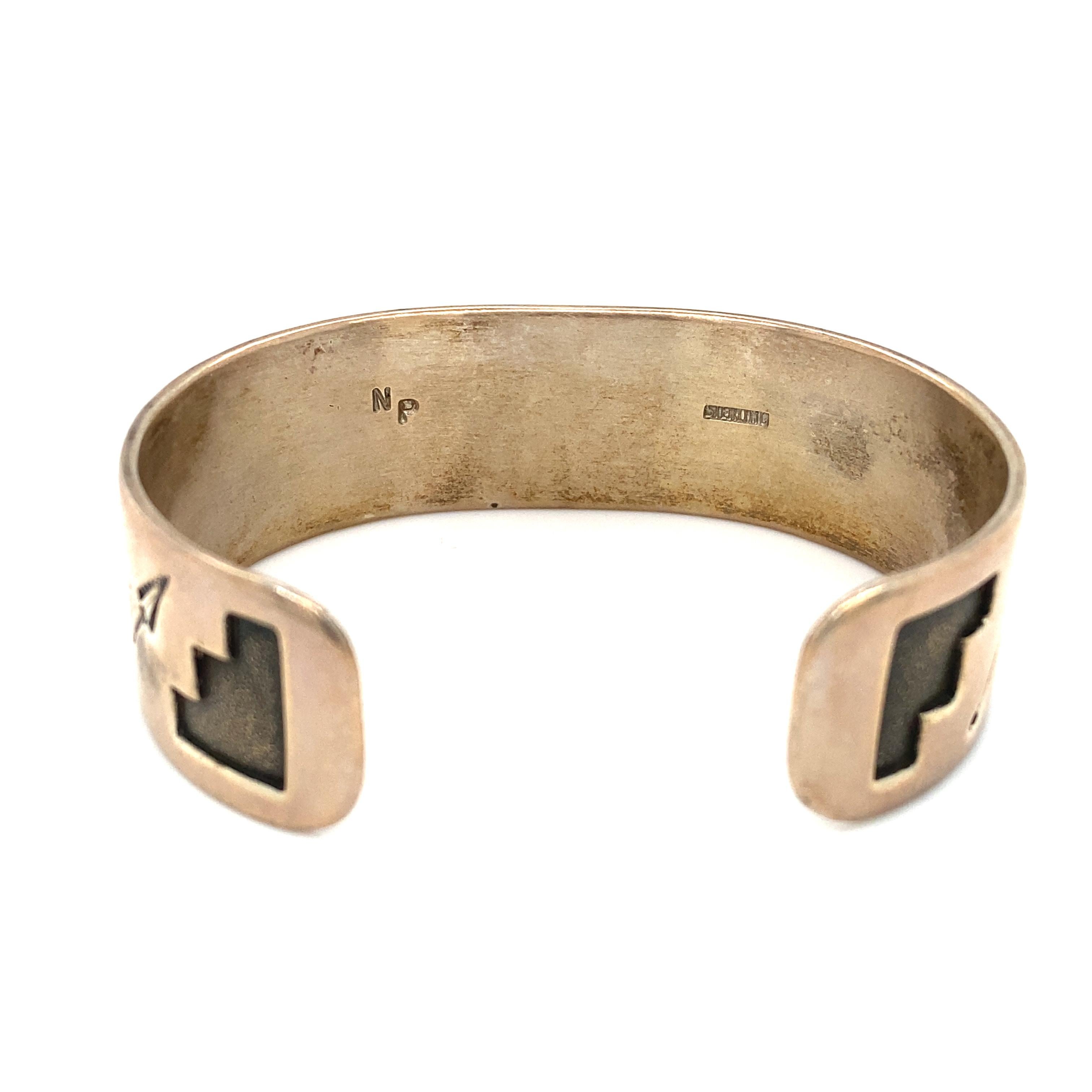 Details zum Artikel: Dieses Manschettenarmband des indianischen Künstlers Neal Paquin zeigt ein Bärenmotiv.

Circa: 1990er Jahre
Metall Typ: Sterling Silber
Gewicht: 38.4 Gramm
Größe: 0,6 Zoll Breite
 