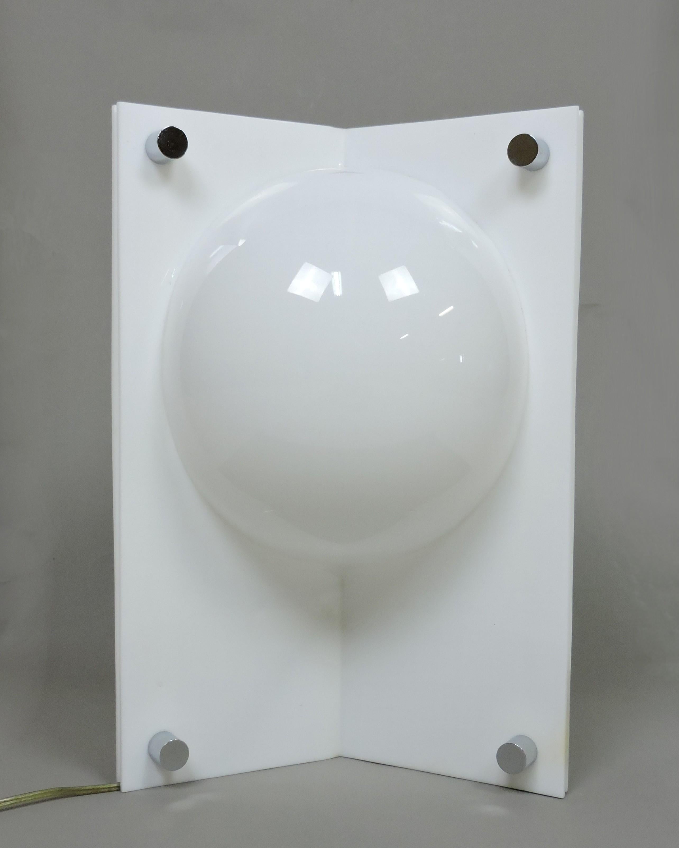 Una lampada da tavolo a tre lati, del 1968 circa, prodotta da Neal Small Designs, Inc., New York. Questa lampada è composta da tre sezioni di lastra acrilica bianca modellata, tenute insieme da una ferramenta cromata, e può ospitare una singola