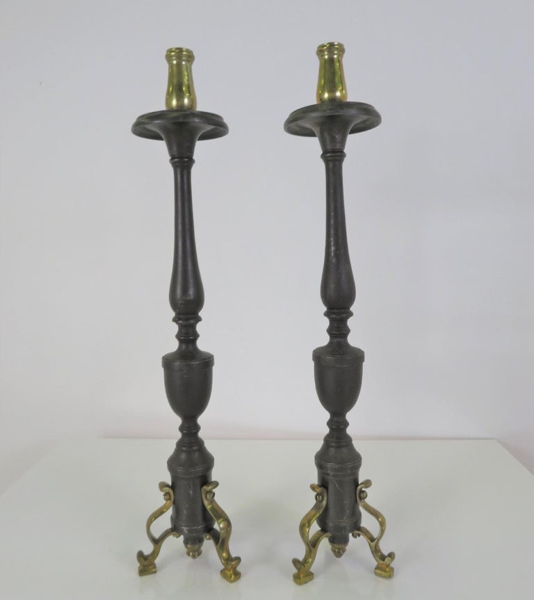 Late Baroque or early Rococo pair of sinuous form bronze Candlesticks. Italian born, they were probably alter pieces and have a subtle decoration on the shiney bronze candleholder top and curlicue bronze legs at the bottom. The tubular centers have
