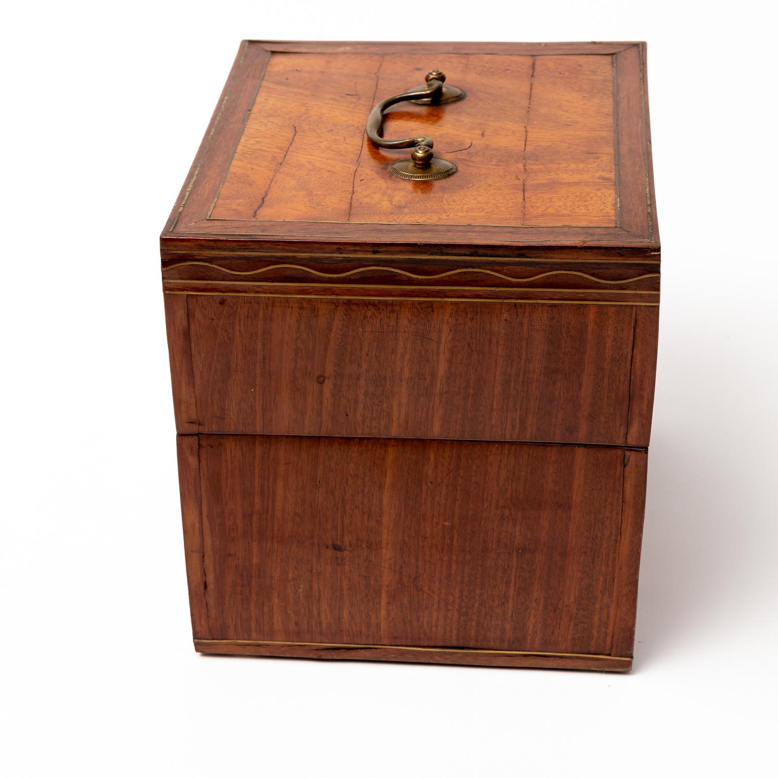 Circa 1790s near cube shaped tantalus cabinet box in the Hepplewhite style which retains four original bottles and three of four original glasses. The interior is also constructed with a square shaped mirror. The box's exterior features Mahogany