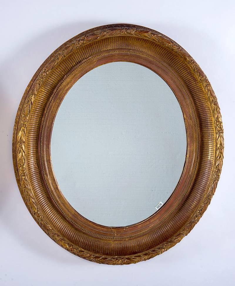 Circa 1880 near pair oval mirrors with wide carved gilt wood and gesso frames. Frames are not perfectly symmetrical but can be used as a pair. Sold and priced as a pair.  Actual Mirror Size:  23.5” h x 19” w
