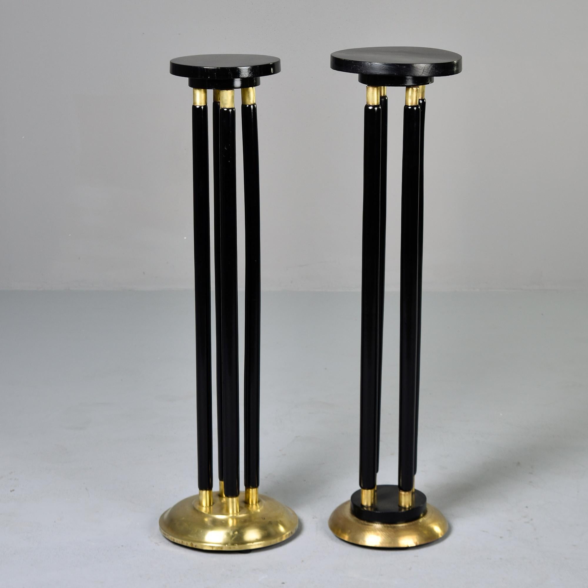 Found in Italy, these circa 1930s tall slender stands feature an ebonised finish and brass trim. Tops are round - larger top is 9.75” diameter. Near pair - there are slight size differences and the trim work on the bases does not match. Unknown